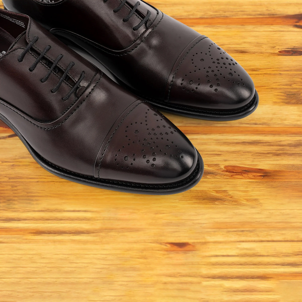 Pair of Burgundy leather dress shoe on a wooden surface
