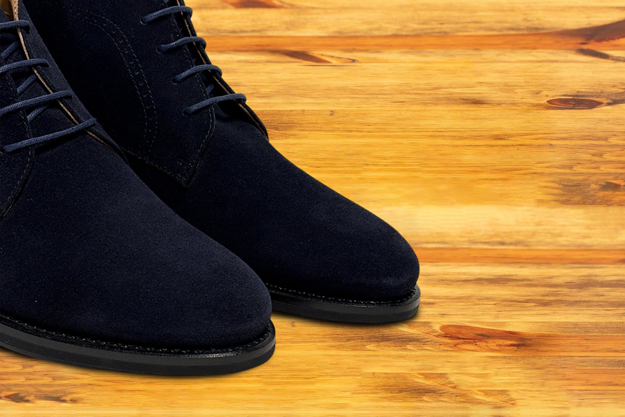 Pair of Navy blue suede shoes on a wooden surface