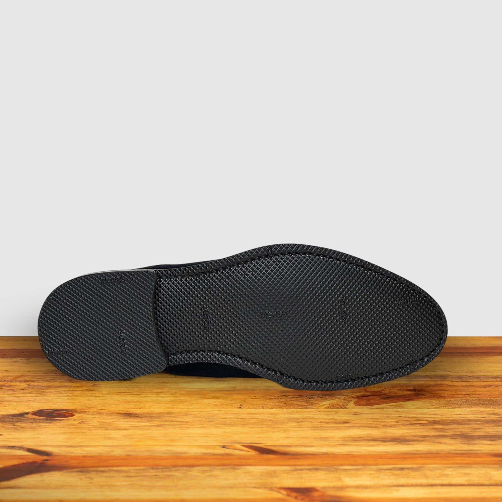 Back of Navy blue suede shoes on a wooden surface with a light gray background