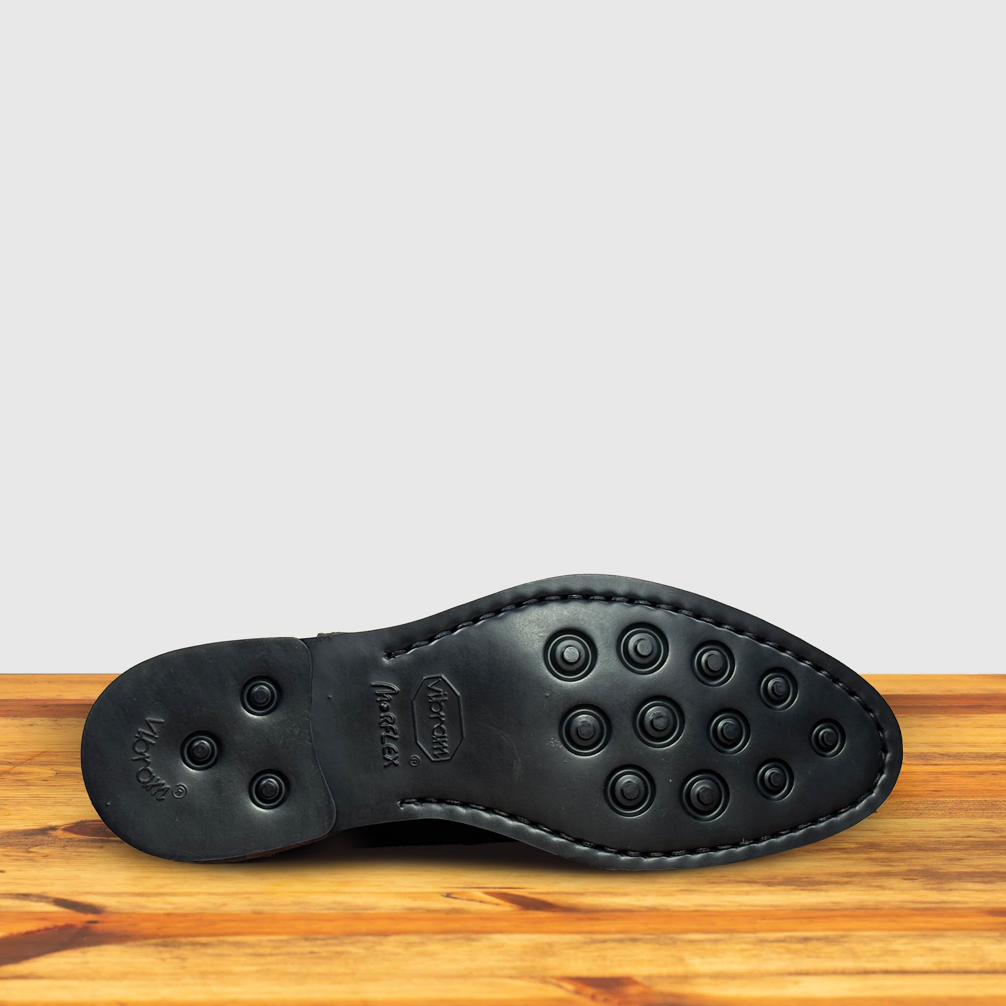 Back of Brown suede Chelsea boot on a wooden surface with a light gray background