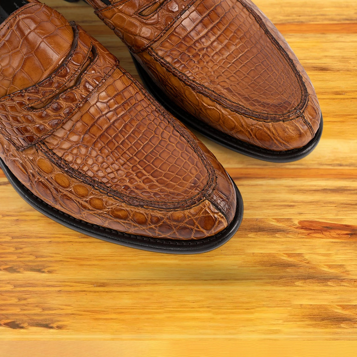 A pair of brick loafers with black soles, displayed on a light wood plank surface.