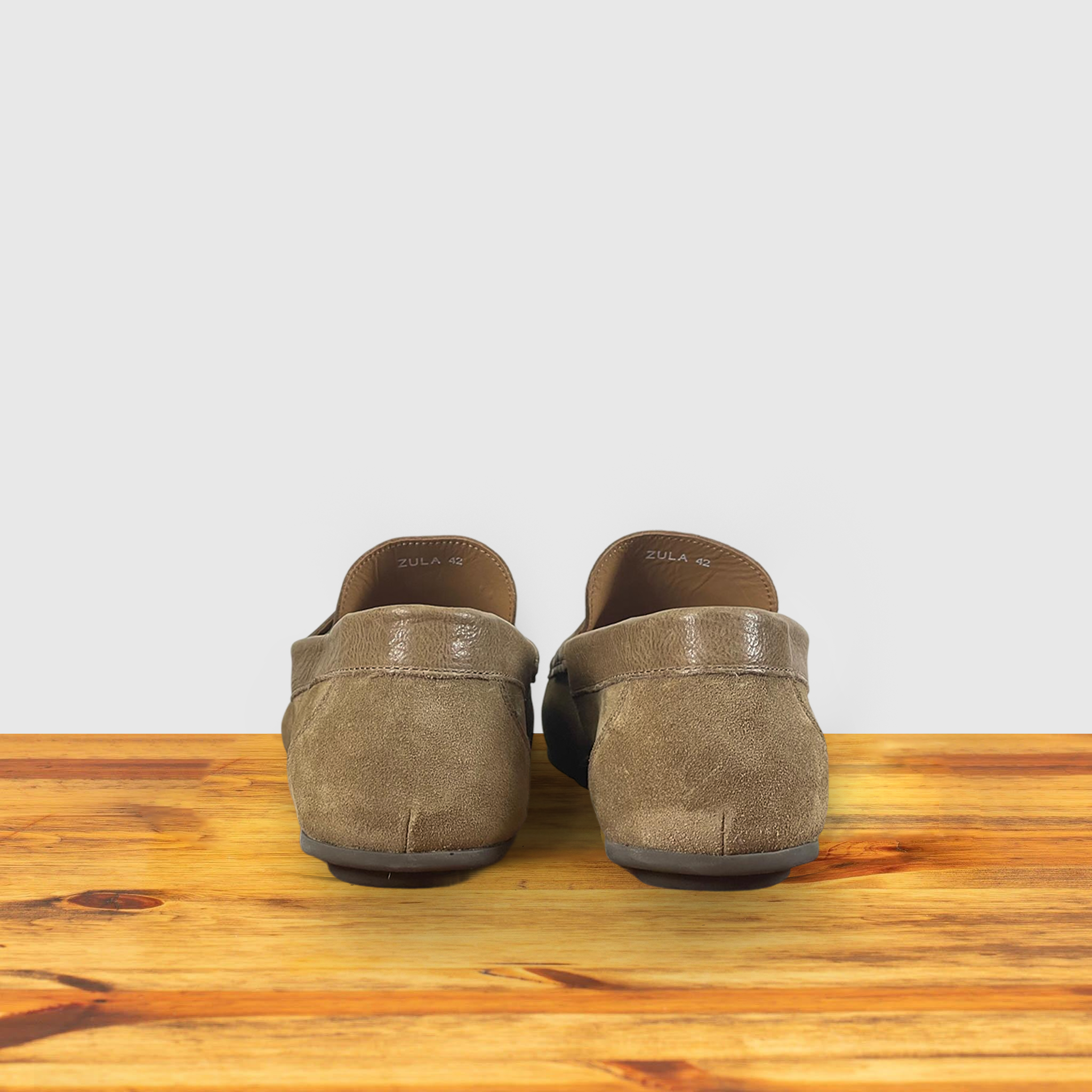 A pair of Rope color suede penny loafer, displayed on a wooden surface.