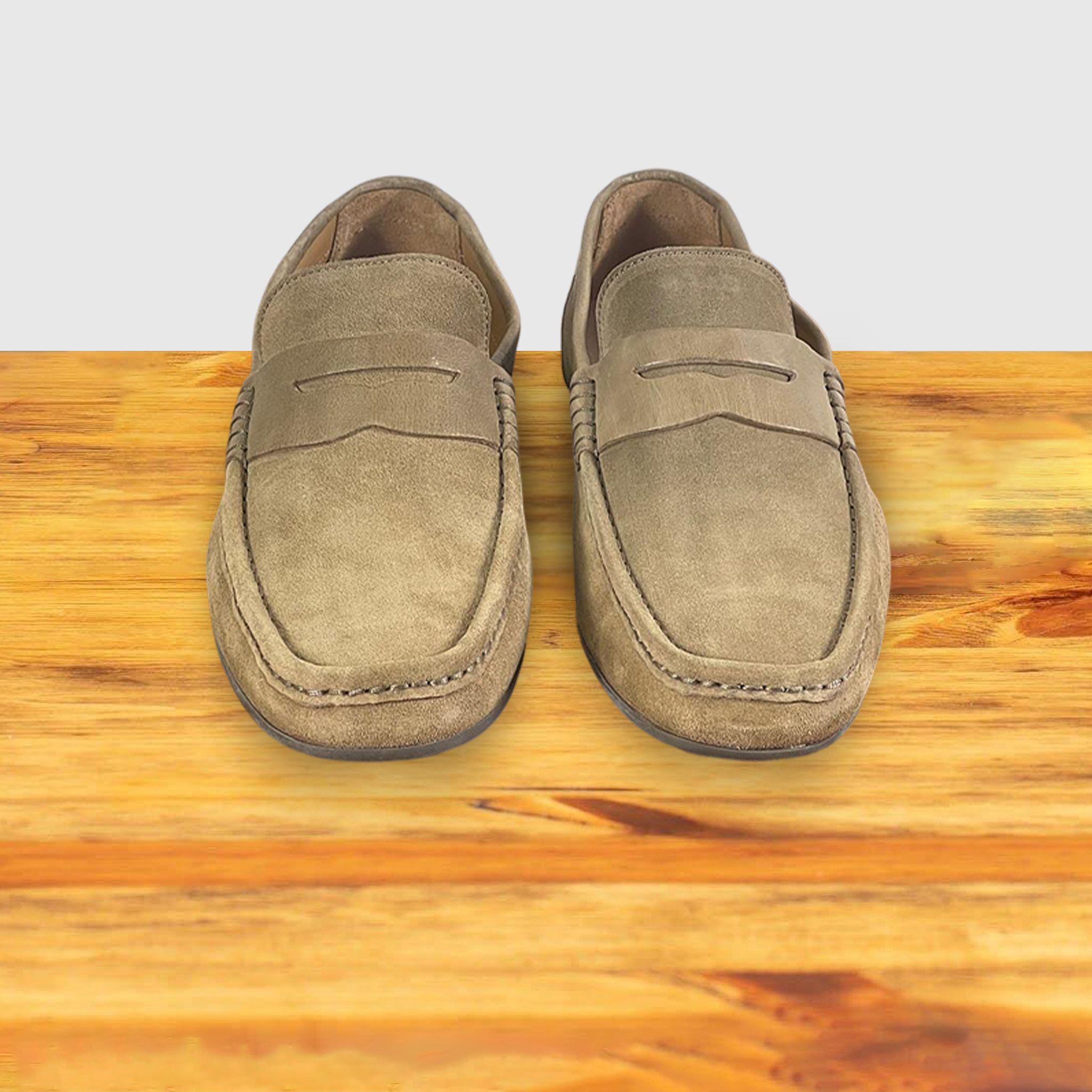 A pair of Rope color suede penny loafer, displayed on a wooden surface.