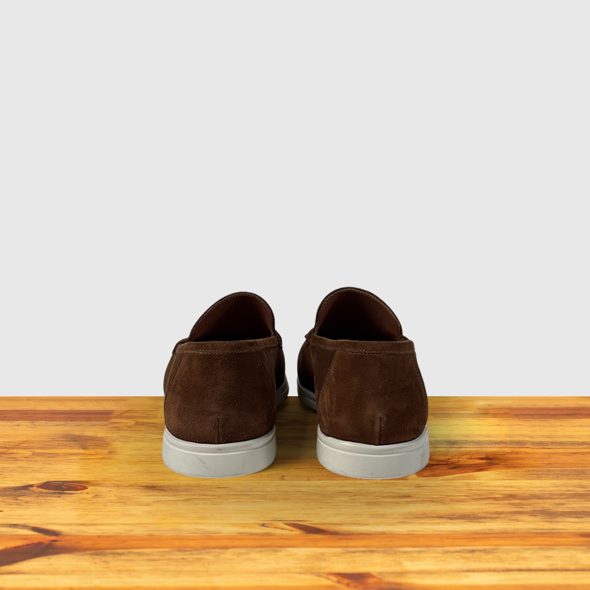 A Brick suede loafer shoe, displayed on a wooden surface.