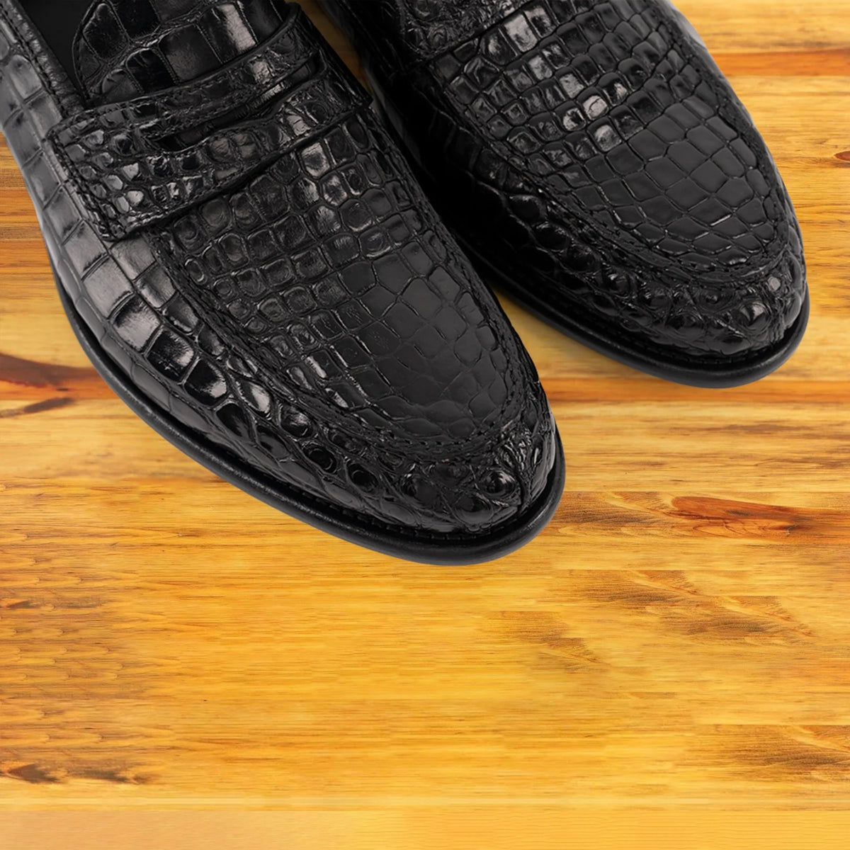 Black leather loafer on a wooden surface