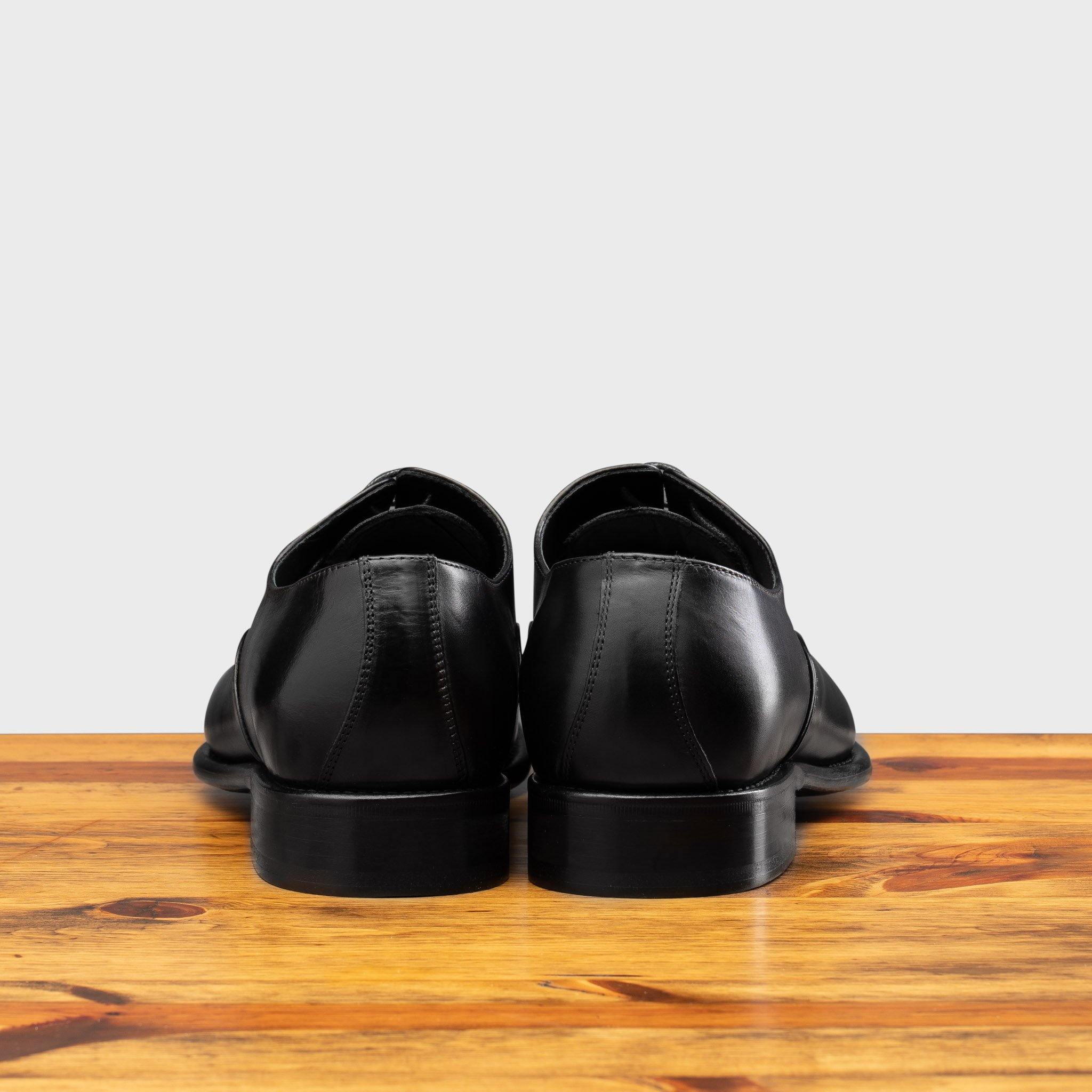 Back profile of the 2361 Calzoleria Toscana Black Cayenne Calf Cap Toe on top of a wooden table