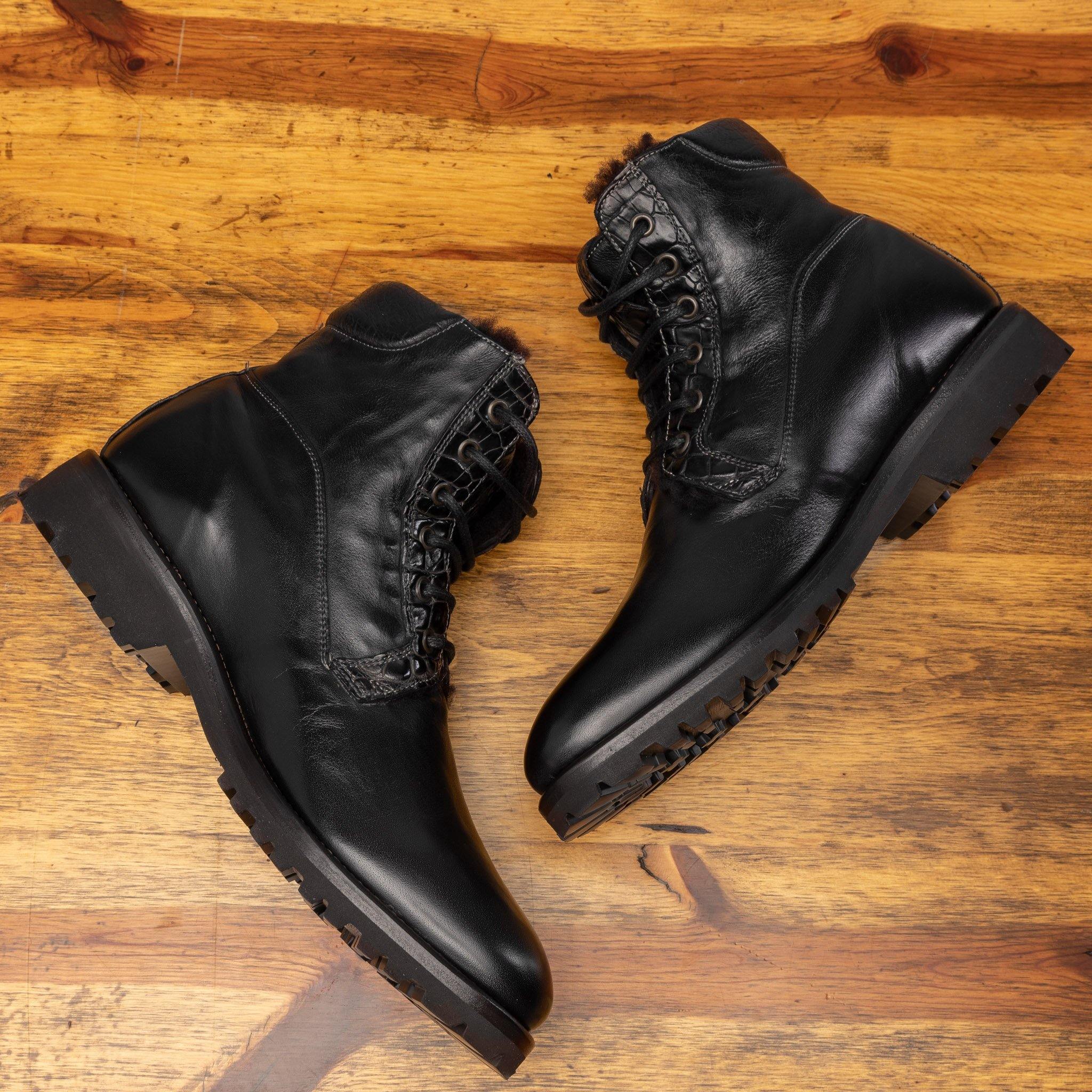Side profile of the pair of the 3236 Calzoleria Toscana Black Shearling Boot laying down on top of a wooden table