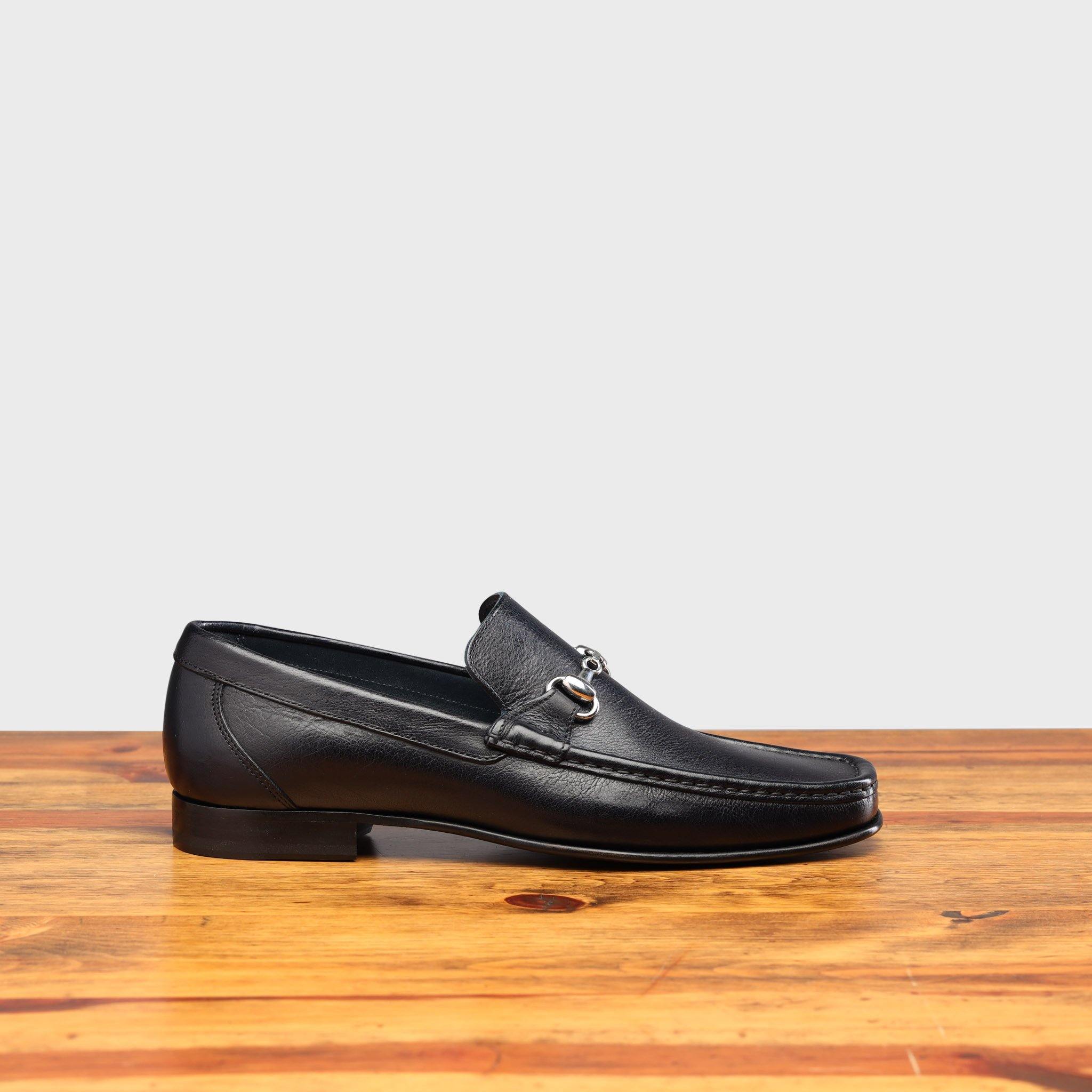 Blue loafer shoe on a wooden surface with a light gray background