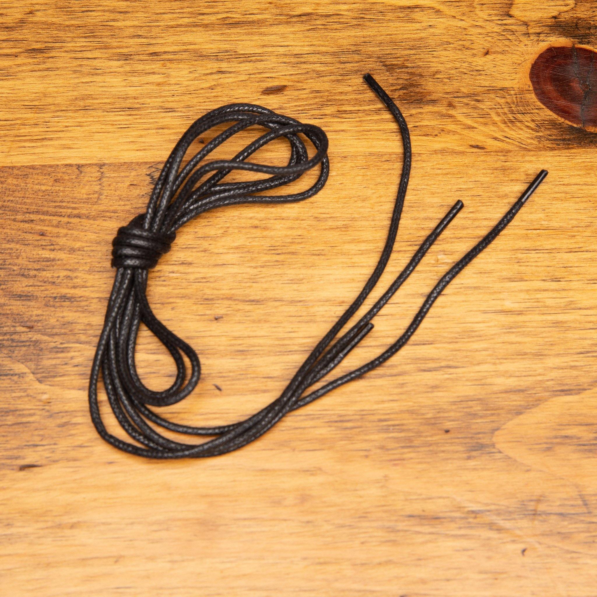 Black Pair of Calzoleria Toscana Waxed Cotton Lace on top of a wooden table