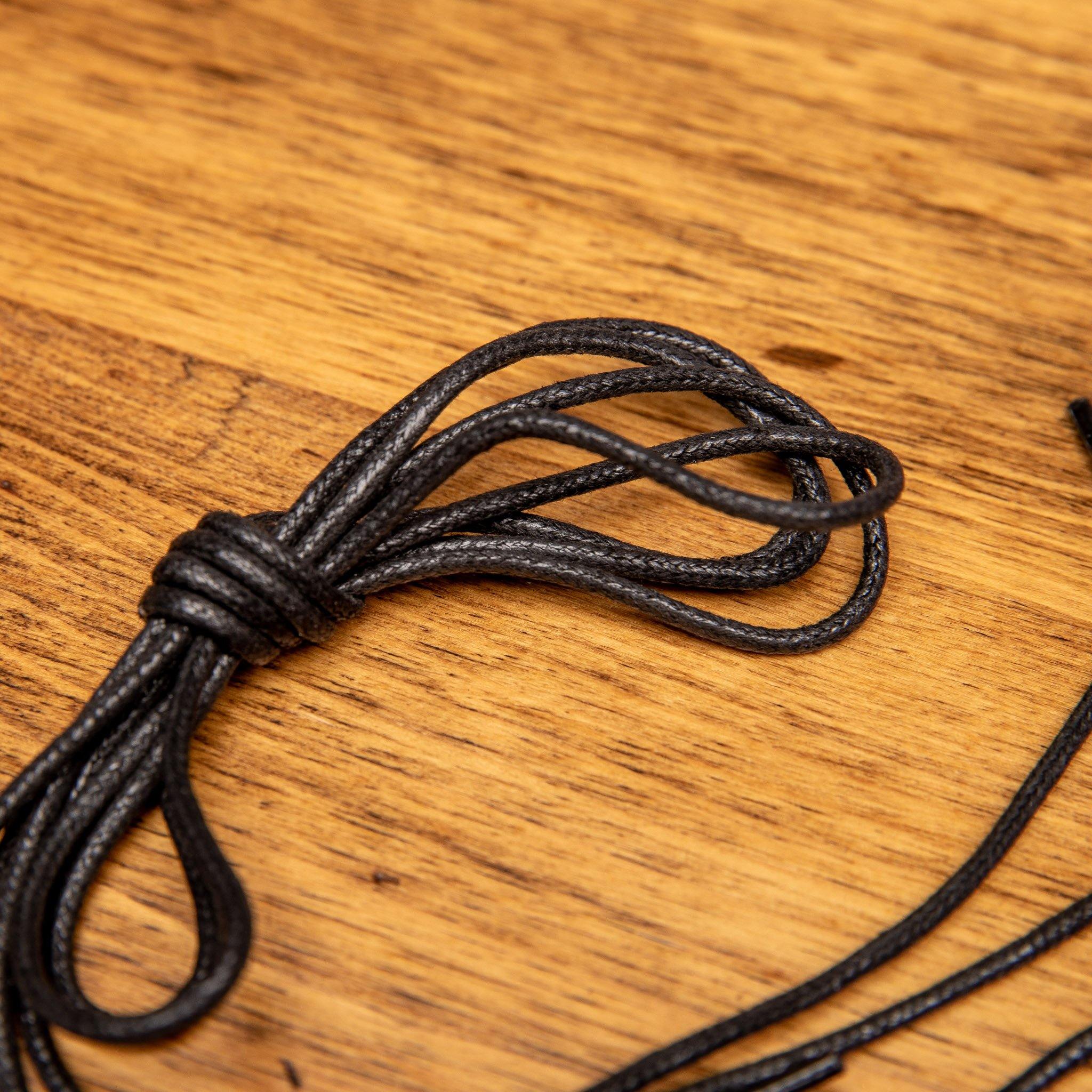 Up close picture of the pair of Black Calzoleria Toscana Waxed Cotton Lace on top of a wooden table