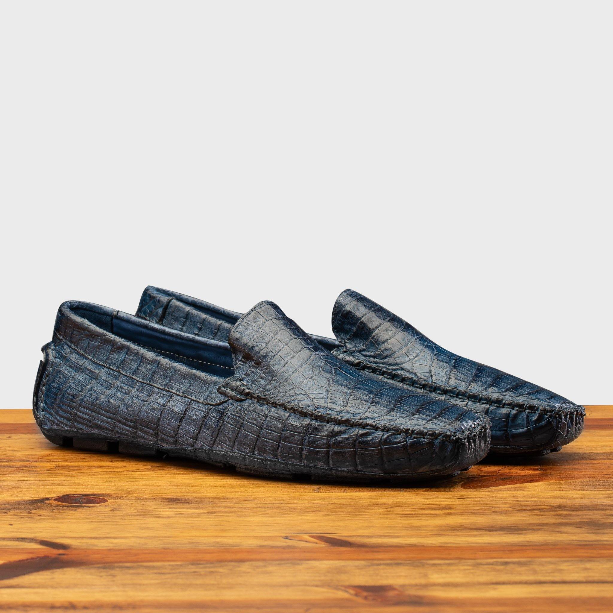 Pair of the 4551 Calzoleria  Toscana Denim Blue Crocodile Dip-Dyed Driver on top of a wooden table