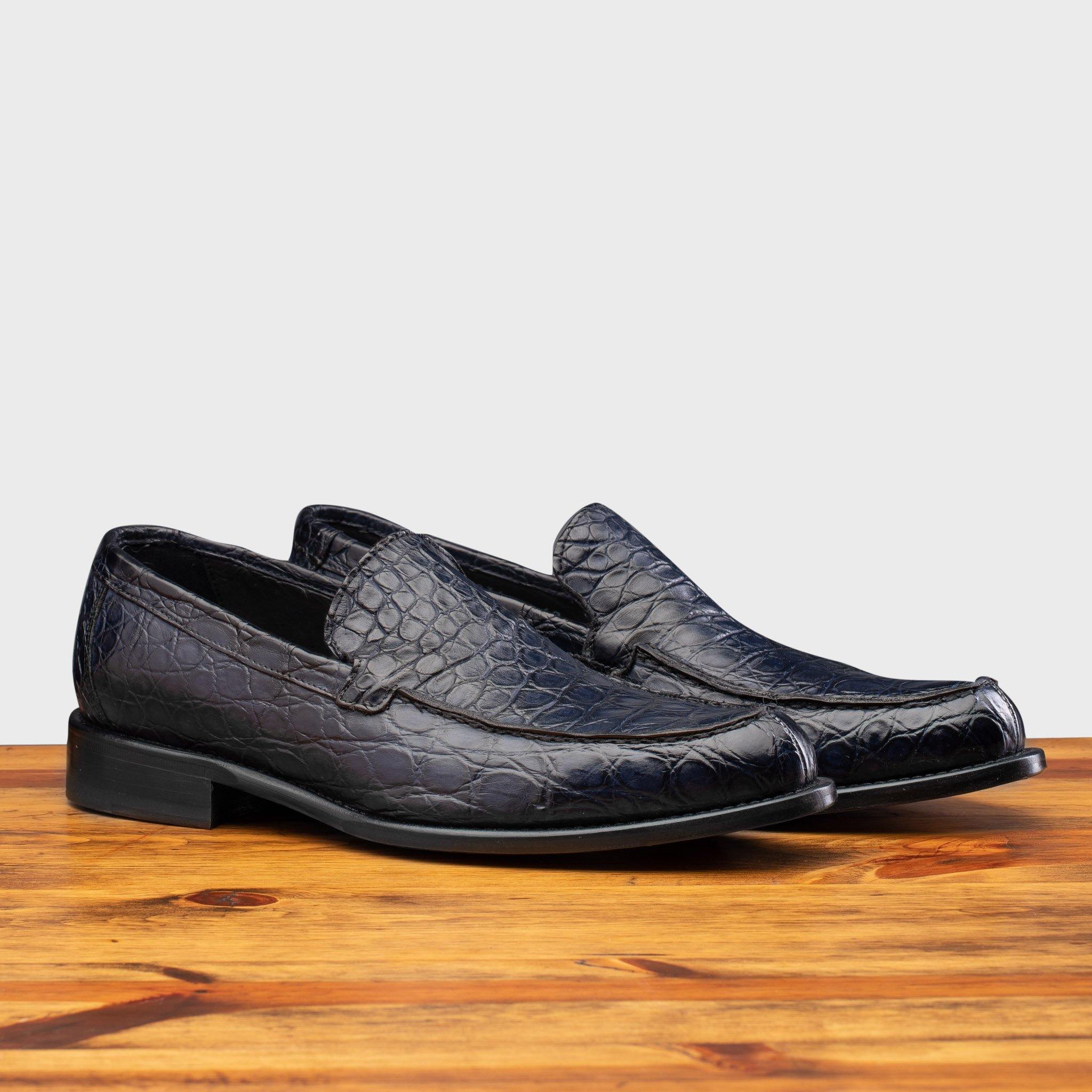 Pair of 5034 Calzoleria Toscana Ocean Blue Crocodile Slip-On on top of a wooden table