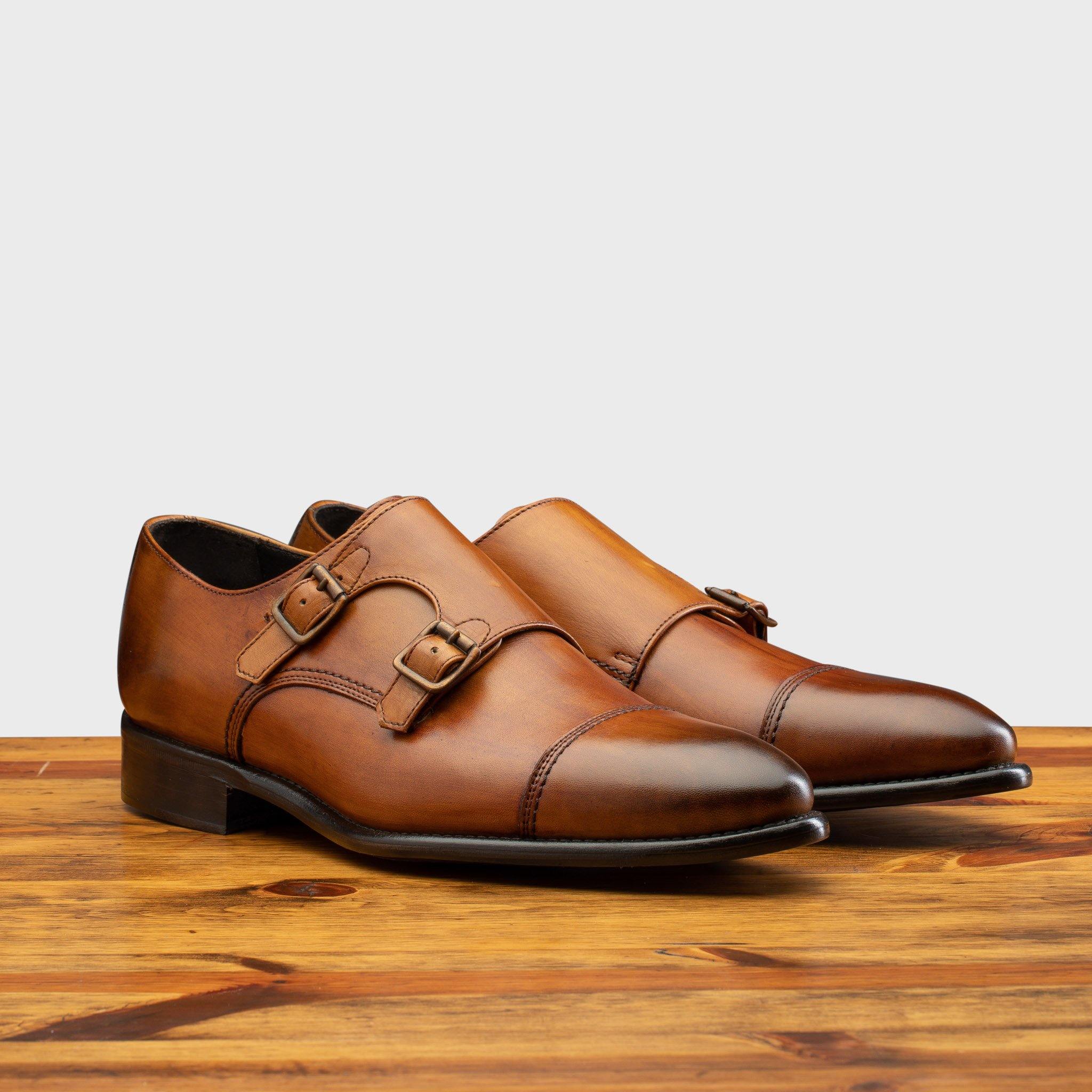 Pair of 6582 Calzoleria Toscana Dark Caramel Monkstrap Cap Toe on top of a wooden table