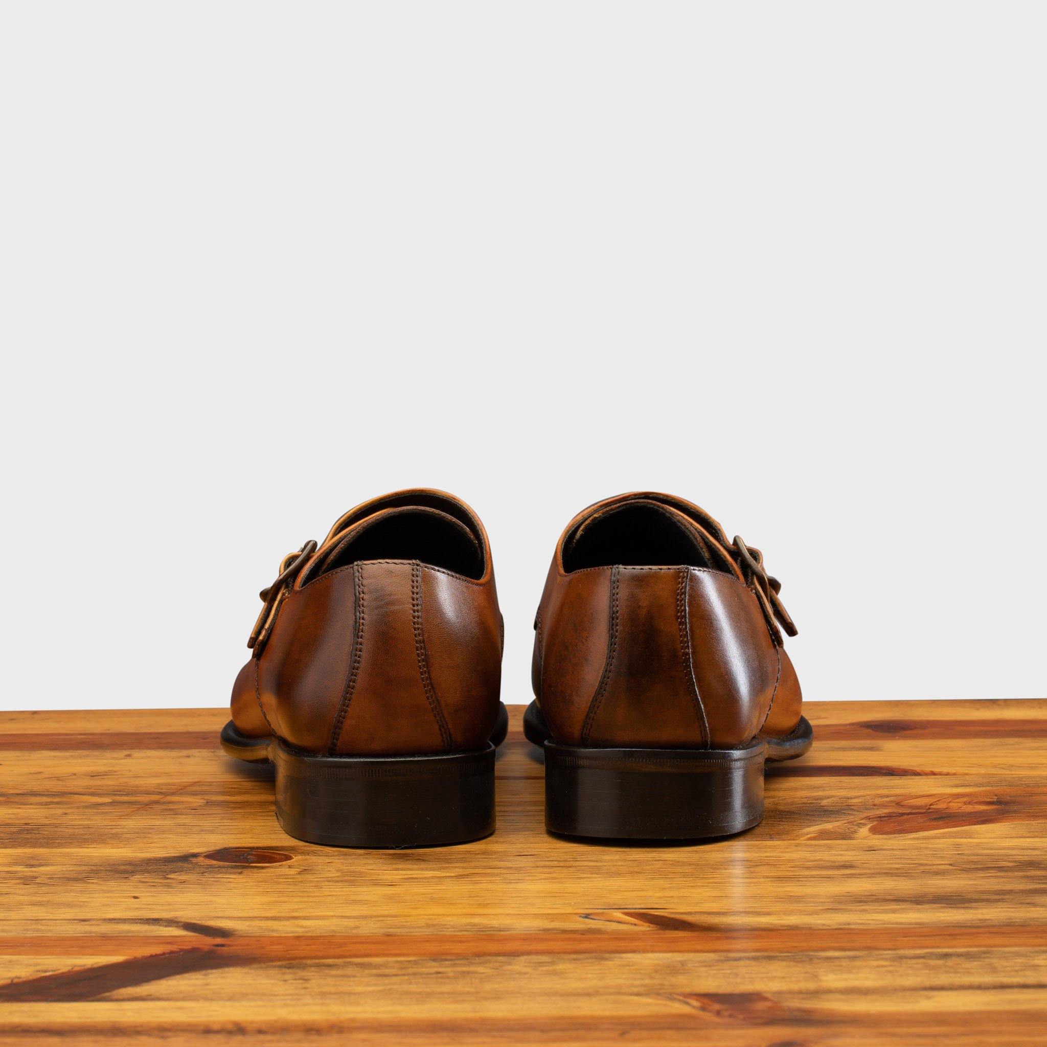 Back profile of 6582 Calzoleria Toscana Dark Caramel Monkstrap Cap Toe on top of a wooden table