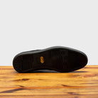 Full Vibram Rubber Gumlite Outsole of 7839 Calzoleria Toscana Black Elba Slip-On on top of a wooden table