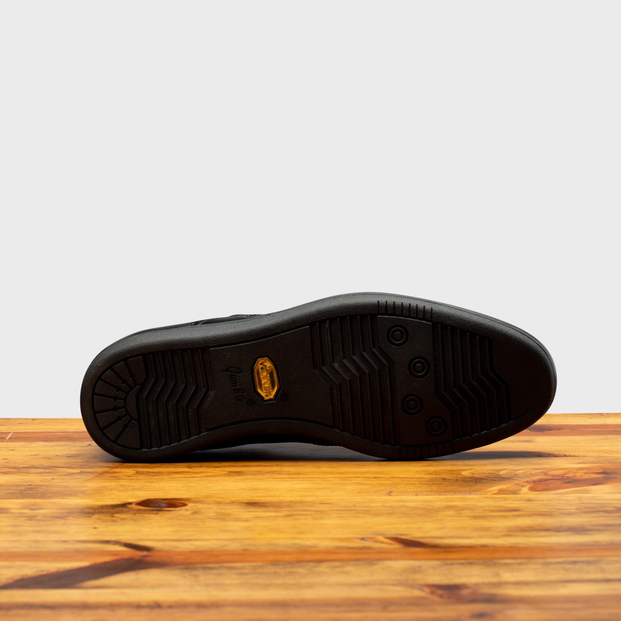 Full Vibram Rubber Gumlite Outsole of 7839 Calzoleria Toscana Black Elba Slip-On on top of a wooden table