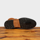 Leather bottom with half Rubber Vibram sole and heel of 9147 Calzoleria Toscana Brick Dip-Dyed Cesar Boot on top of a wooden table
