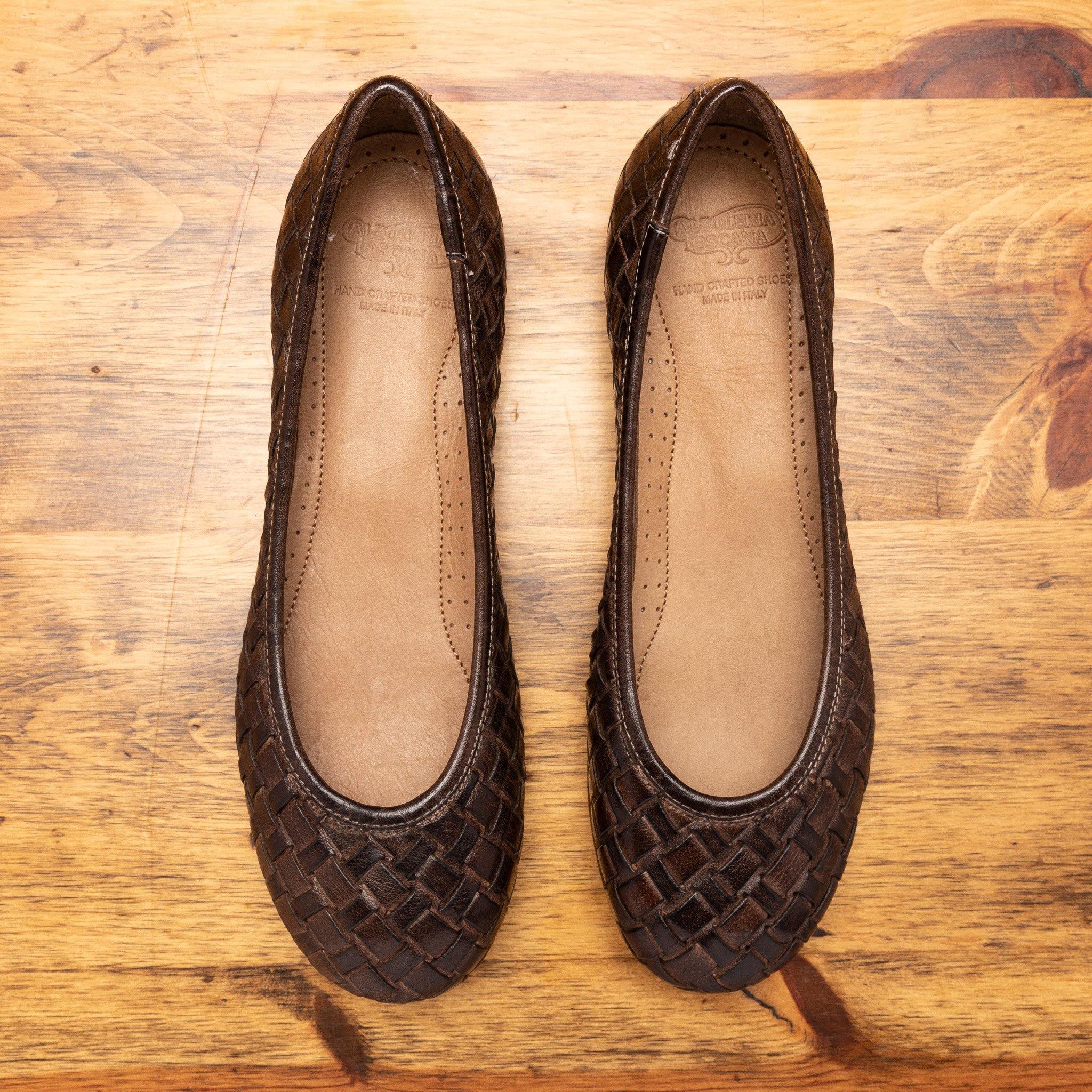 Pair of B940 Calzoleria Toscana Tobacco Melania Ballerina laying flat showing the branded name insole on top of wooden table