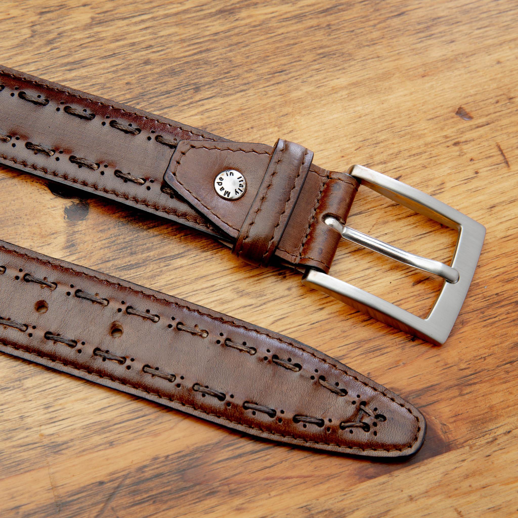 Up close picture of the silver buckle and artisan stitched details on C1482 Cazloeria Toscana Stitched Dress Belt on top of a wooden table