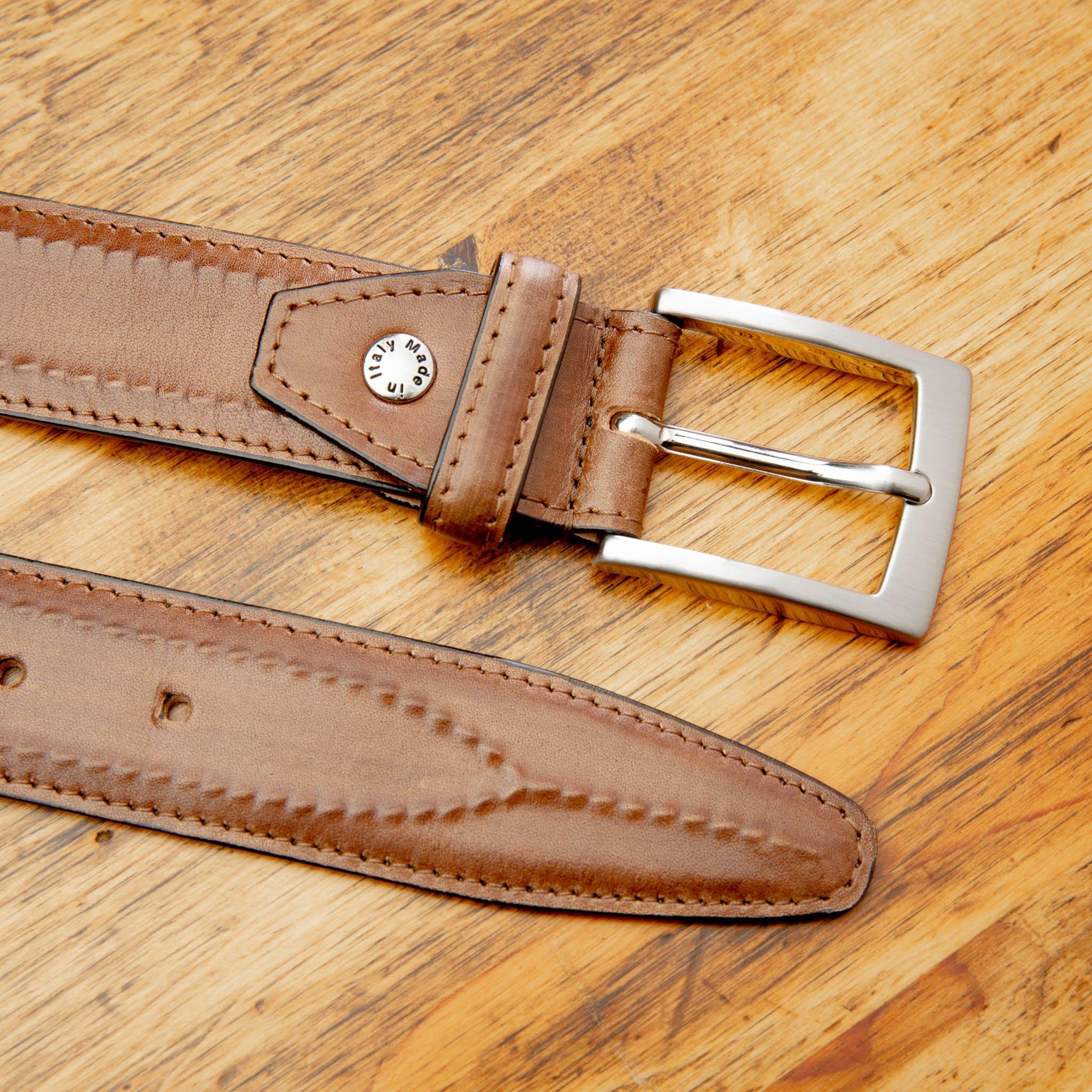 Up close picture of the silver buckle of C2216 Calzoleria Toscana Inner Stitched Dress Belt on top of a wooden table