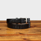 Front profile of C7981 Calzoleria Toscana Black Exotic Hornback Belt on top of a wooden  table