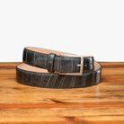 Front profile of C8099 Calzoleria Toscana Gray Crocodile Belt curled up on top of a wooden table