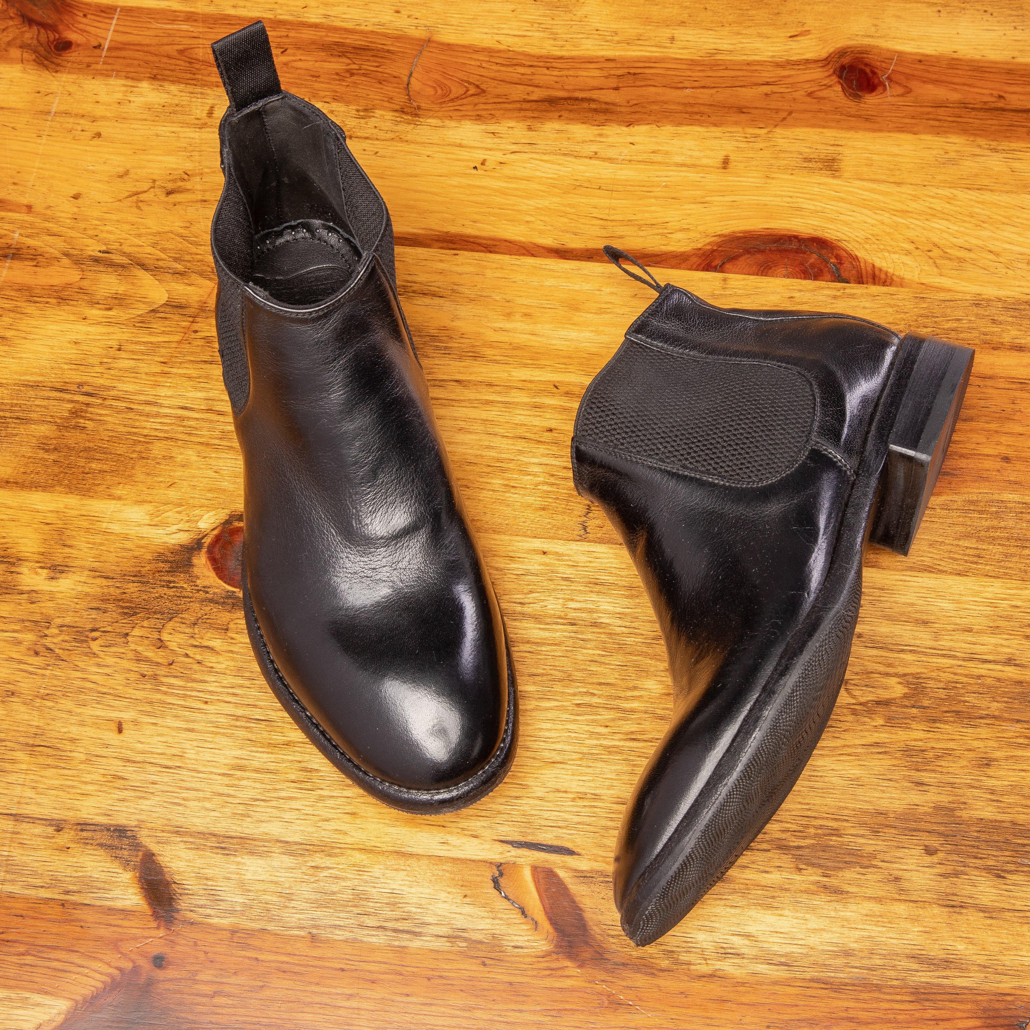 Pair of D367 Calzoleria Toscana Women's Black Chelsea Boot showing the side and front profile on top of a wooden table