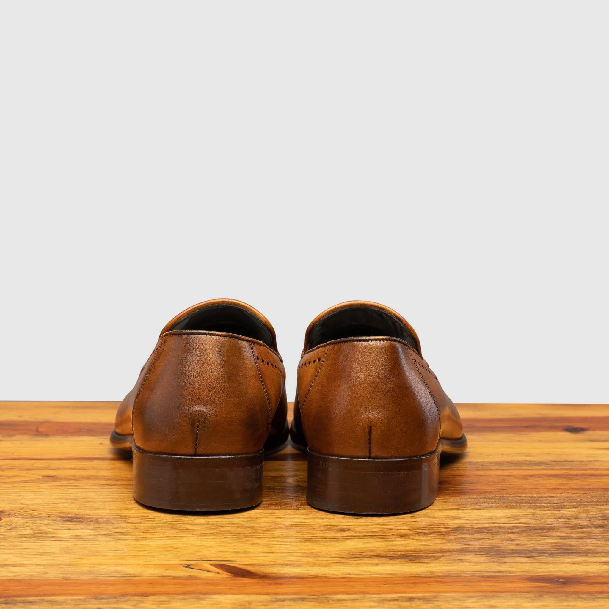 Back profile of H614 Calzoleria Toscana Chestnut Tassel Slip-On on top of a wooden table