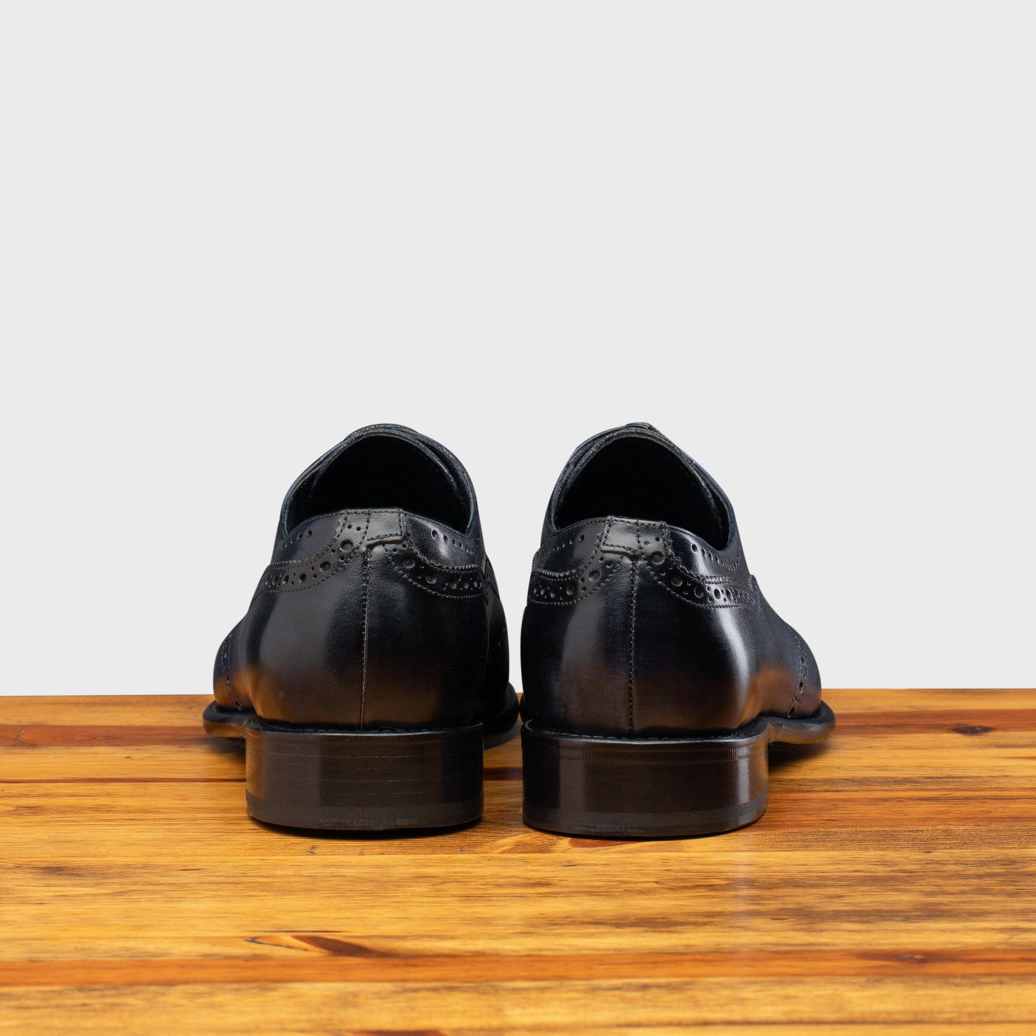 Back view of Blue leather dress shoe on a wooden surface with a light gray background