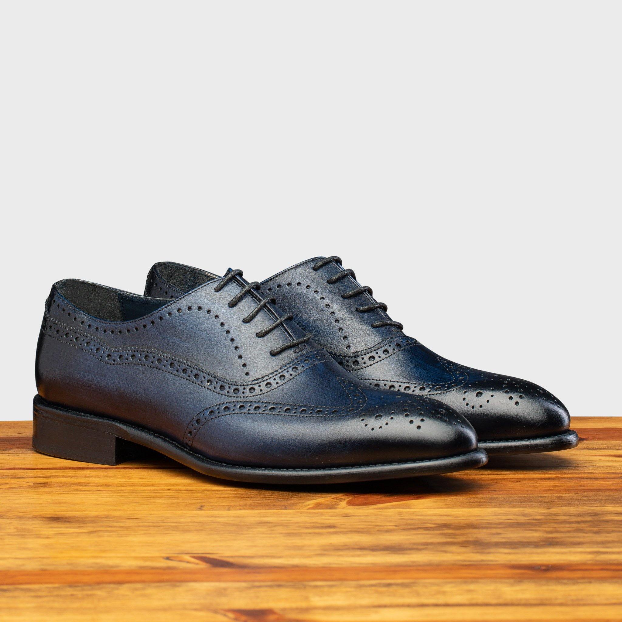 Pair of Blue leather dress shoe on a wooden surface with a light gray background
