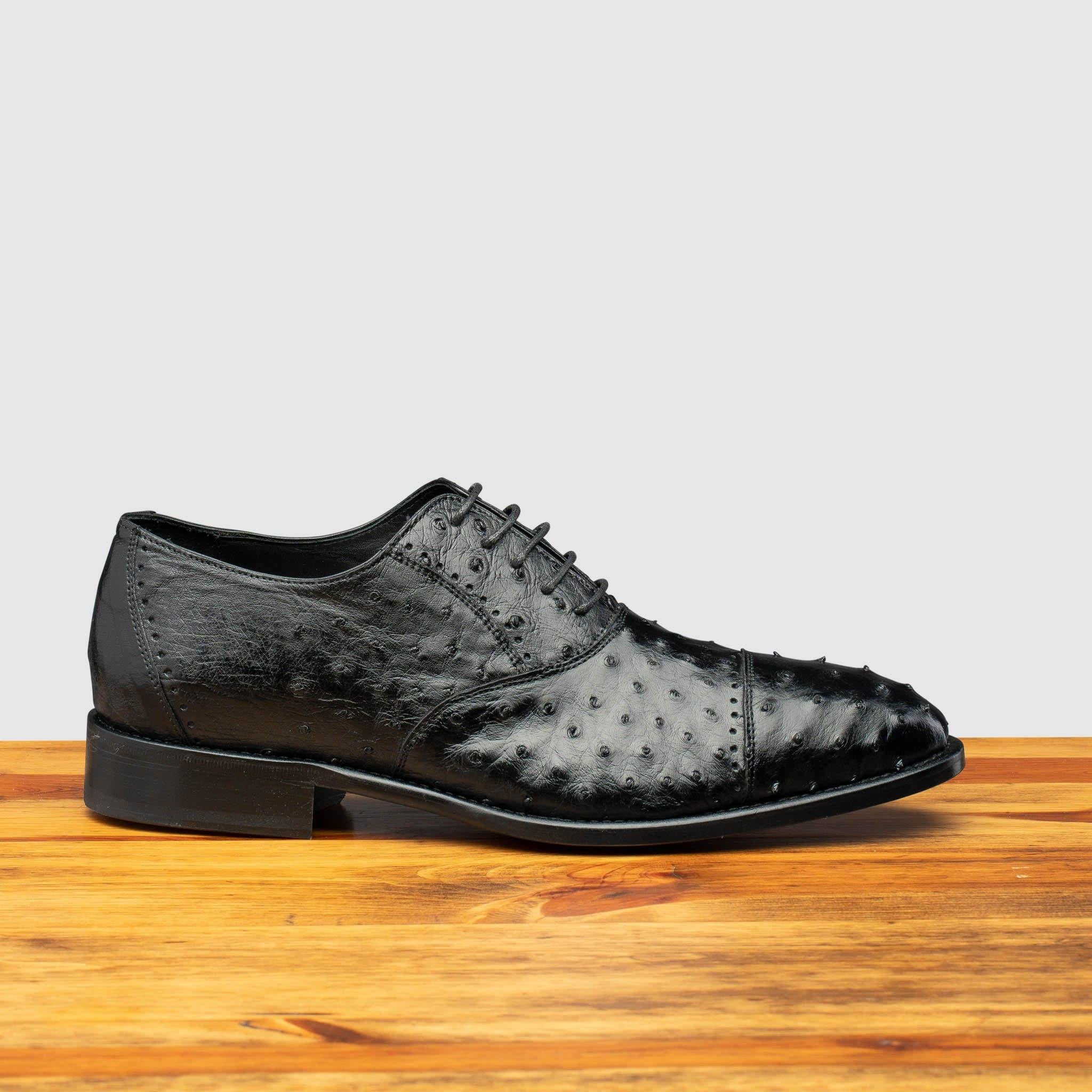 Side profile of H777 Calzoleria Toscana Black Ostrich Cap Toe on top of a wooden table