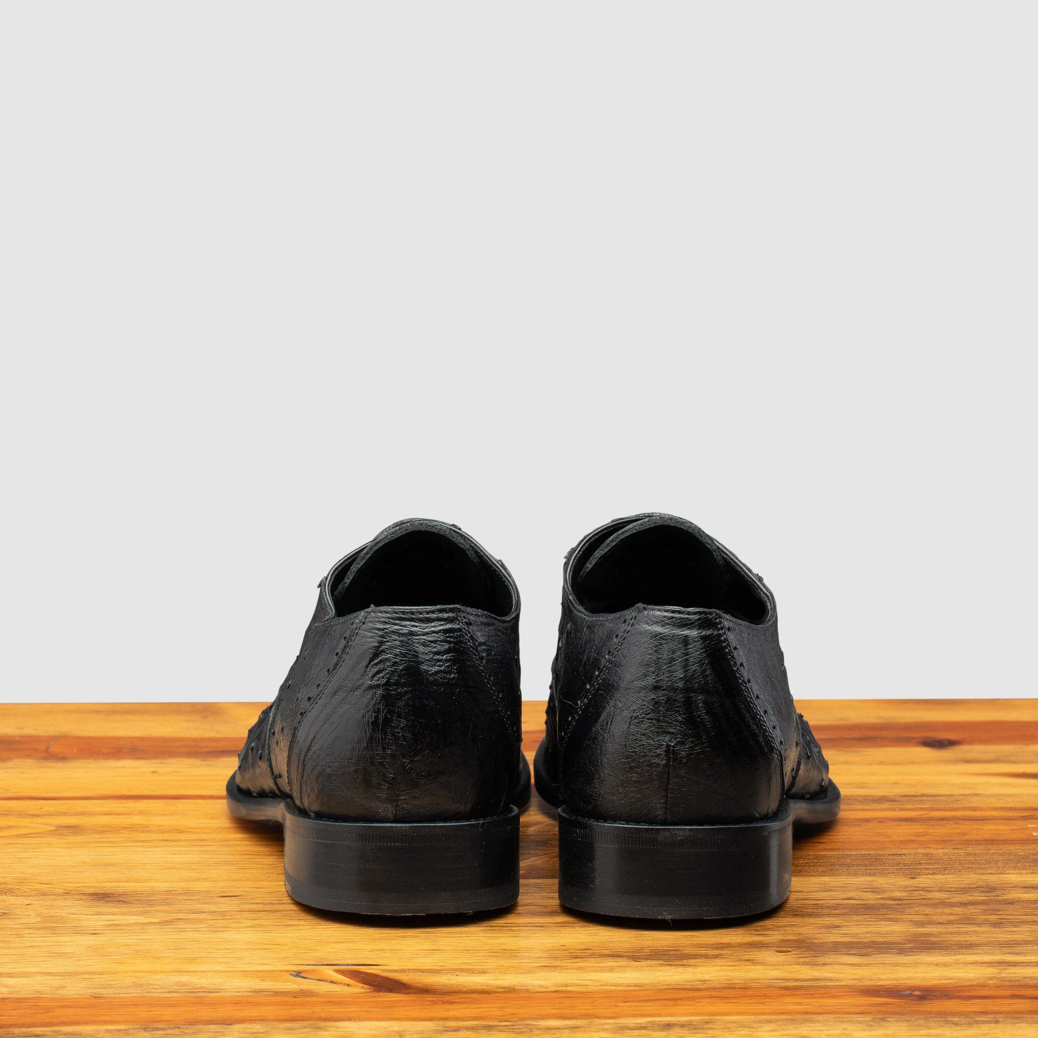 Back profile of H777 Calzoleria Toscana Black Ostrich Cap Toe on top of a wooden table