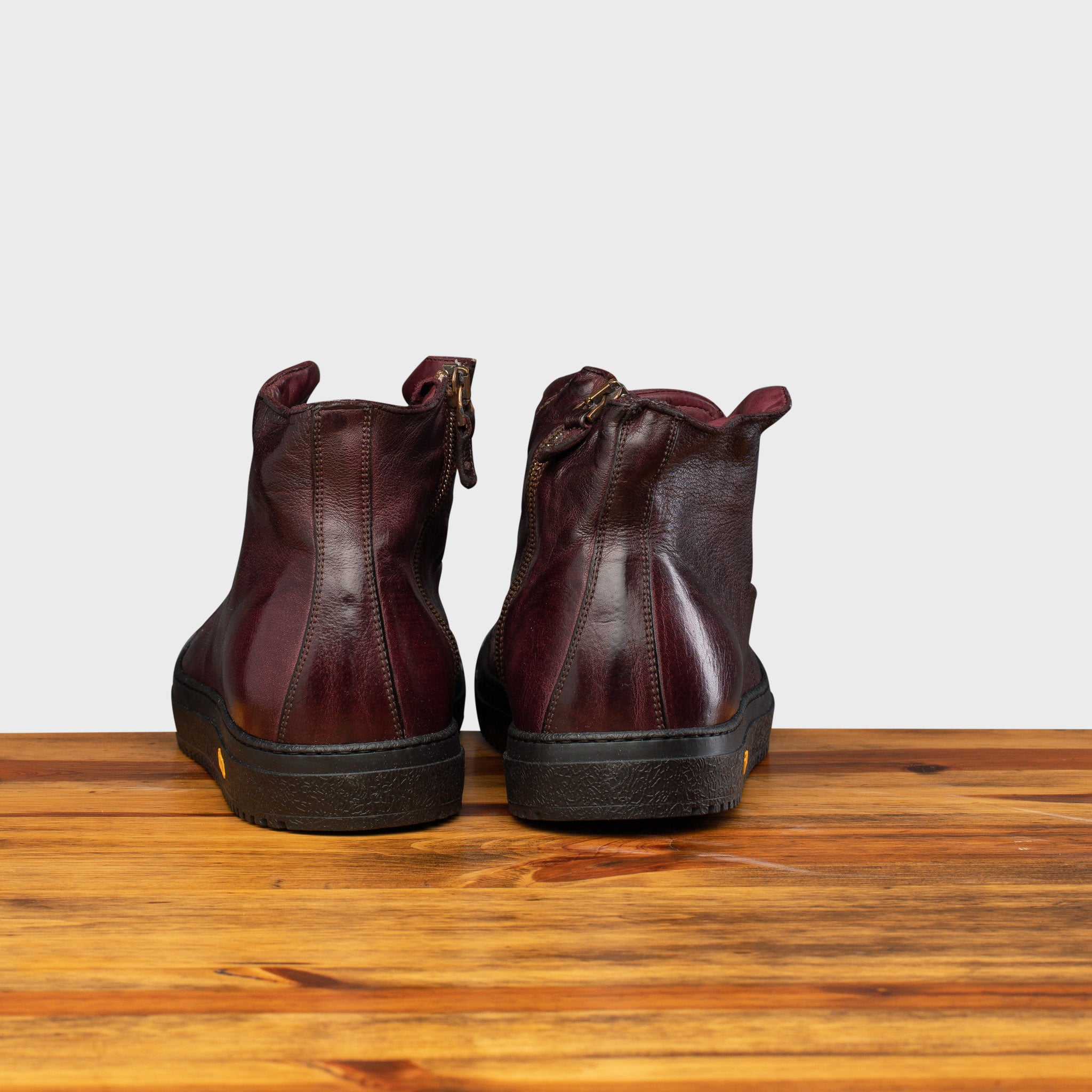 Back profile of H883 Calzoleria Toscana Liver High Top Benso Sneaker on top of a wooden table