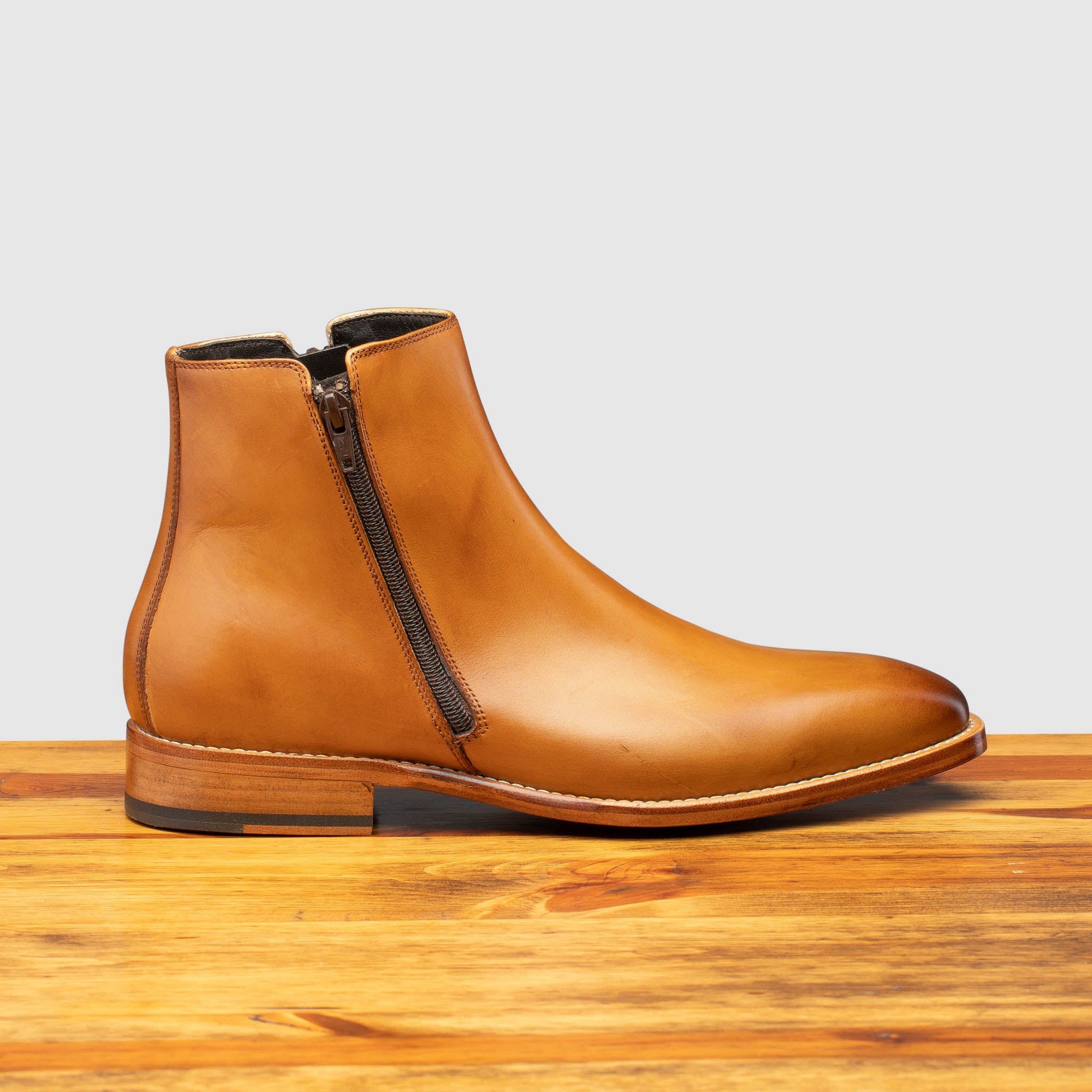 Side profile showing functional zipper  of Q337 Calzoleria Toscana Chester Onice Double Zipper Boot on top of a wooden table