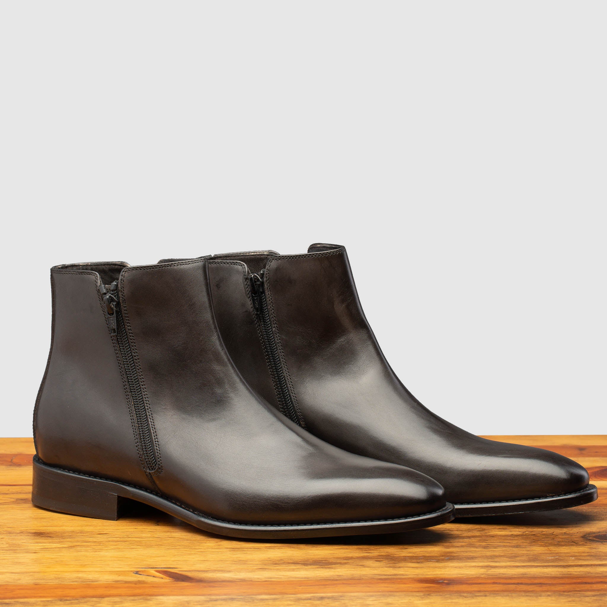 Pair of Q337 Calzoleria Toscana Stone Onice Double Zipper Boot on top of a wooden table