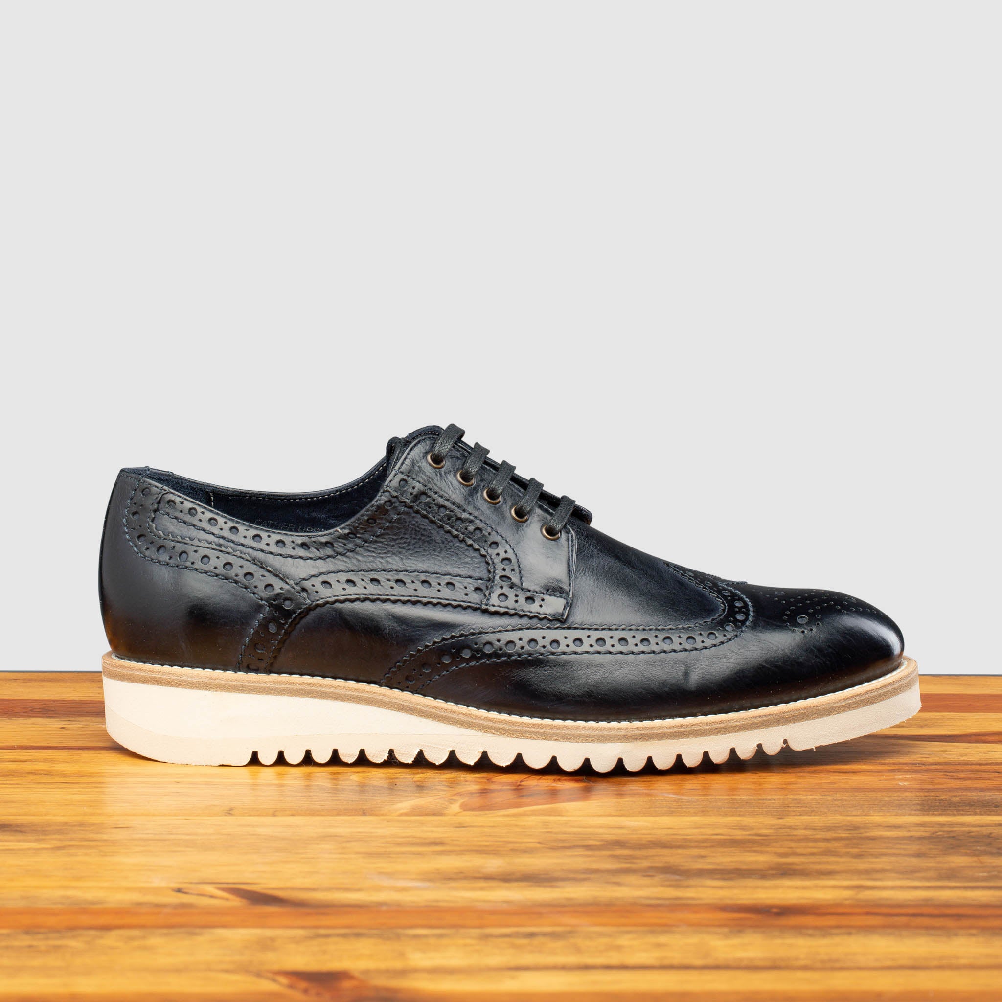 Side profile of Q399 Calzoleria Toscana Blue Agos Wingtip Blucher on top of a wooden table