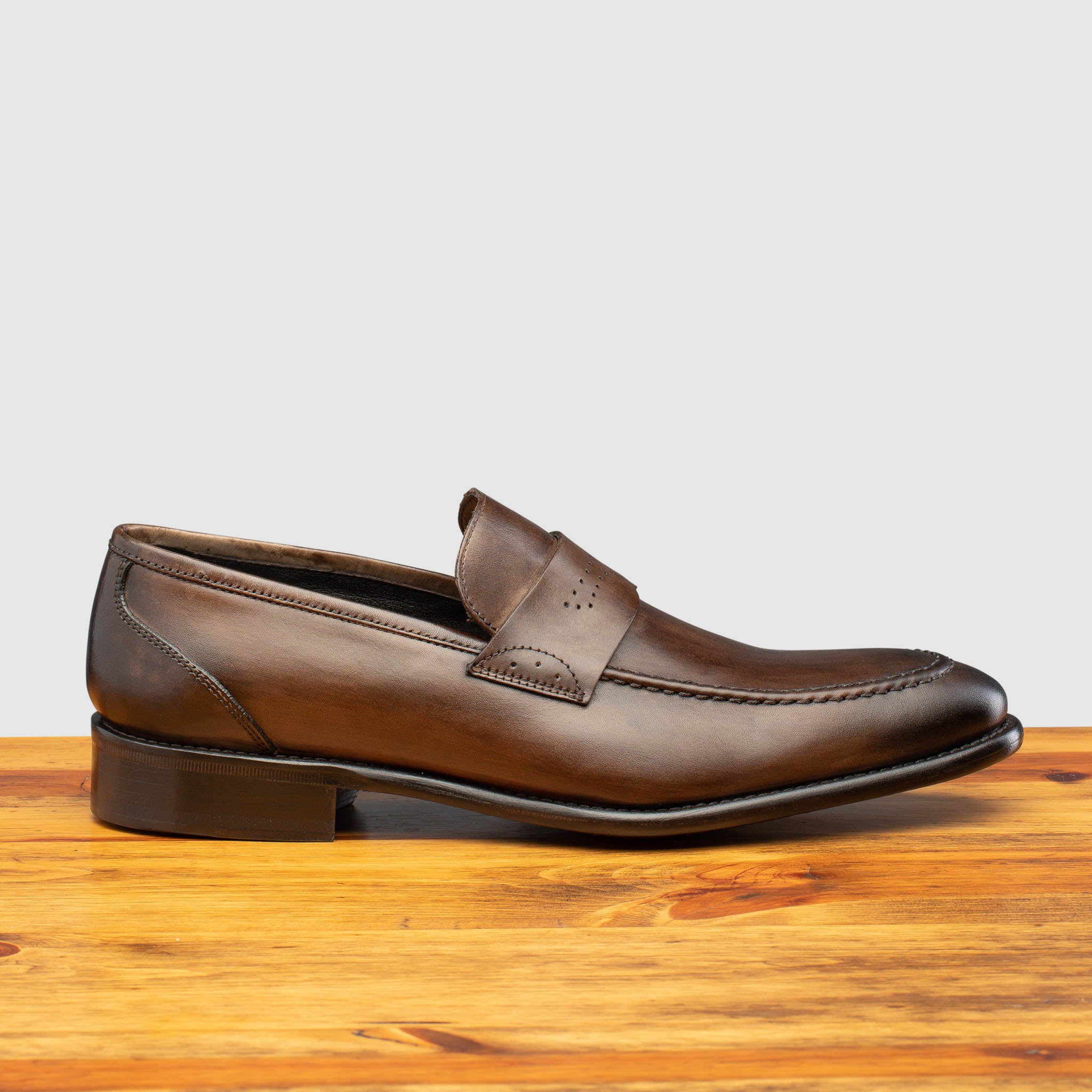Moor leather loafer on a wooden surface with a light gray background