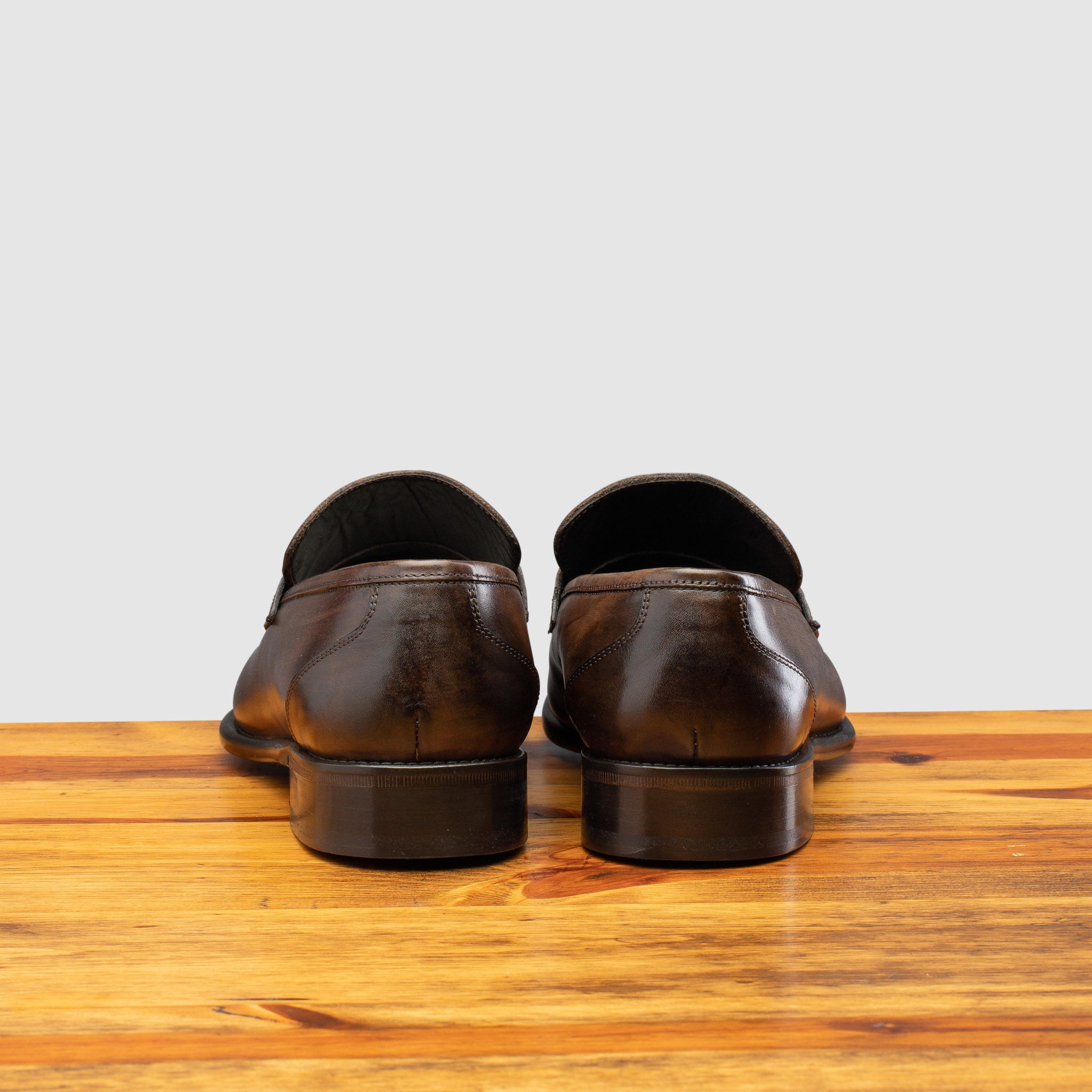 A pair of Moor leather loafer on a wooden surface with a light gray background