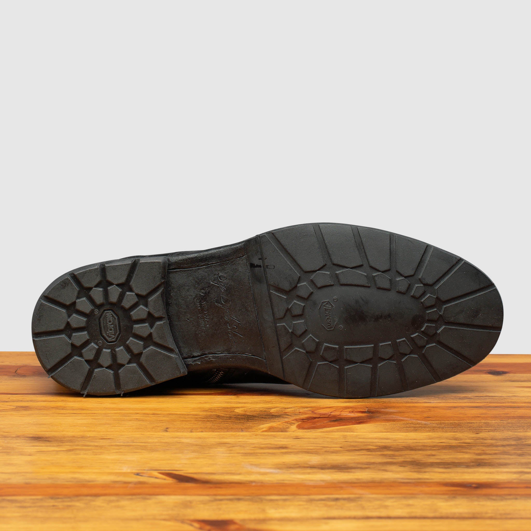 Leather Bottom with half rubber Vibram sole and heel of Q549 Calzoleria Toscana Black Combat Boot on top of a wooden table