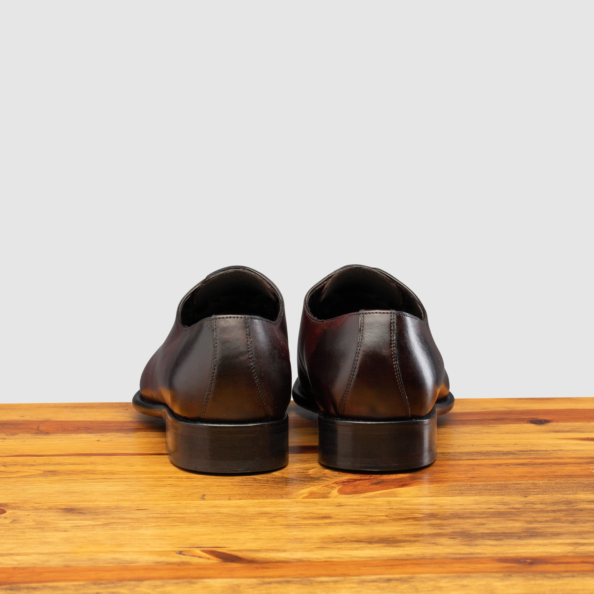Back profile of Q550 Calzoleria Toscana Burgundy (Porpora) Cayenne Calf Wholecut on top of a wooden table
