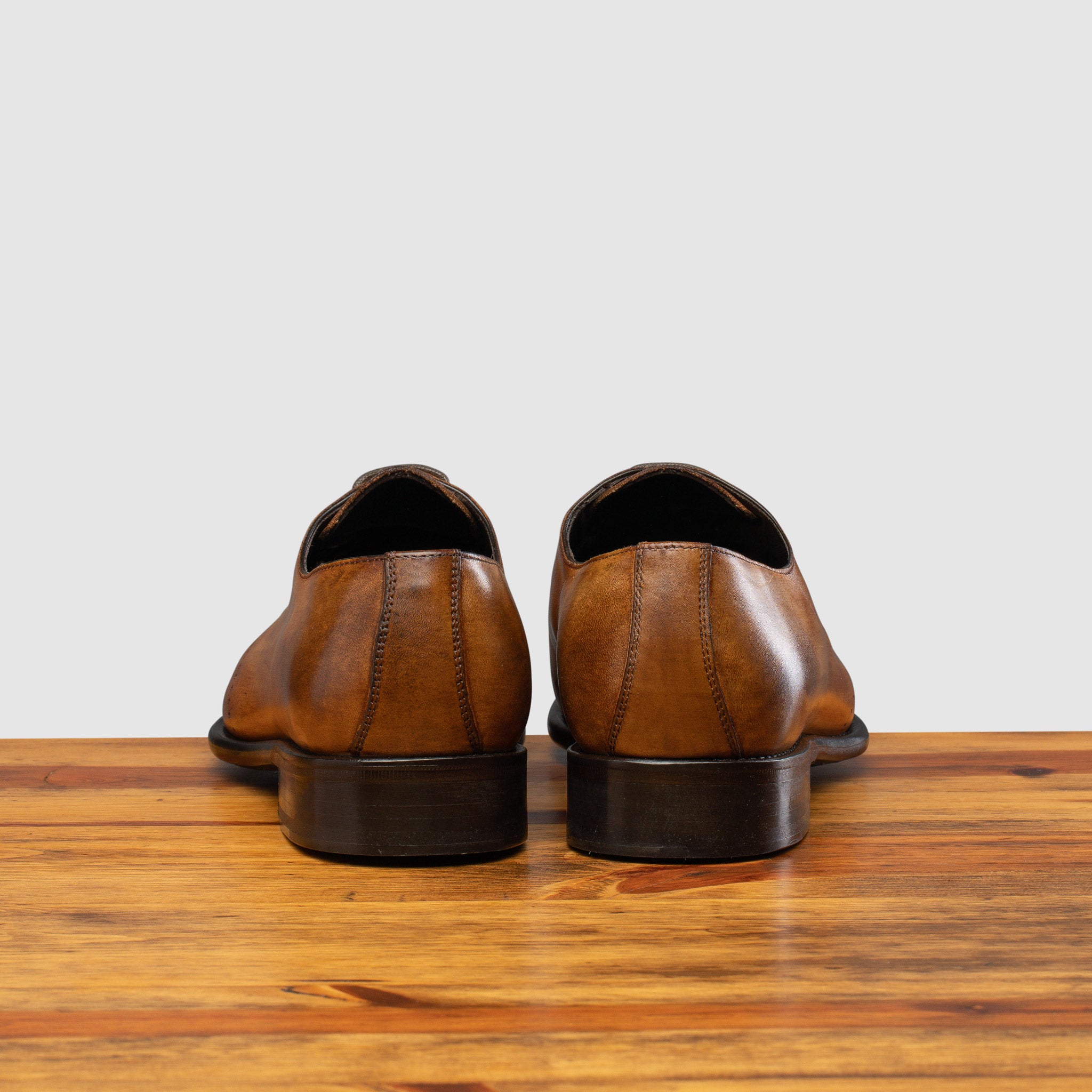 Back profile of Q550 Calzoleria Toscana Chestnut Cayenne Calf Wholecut on top of a wooden table