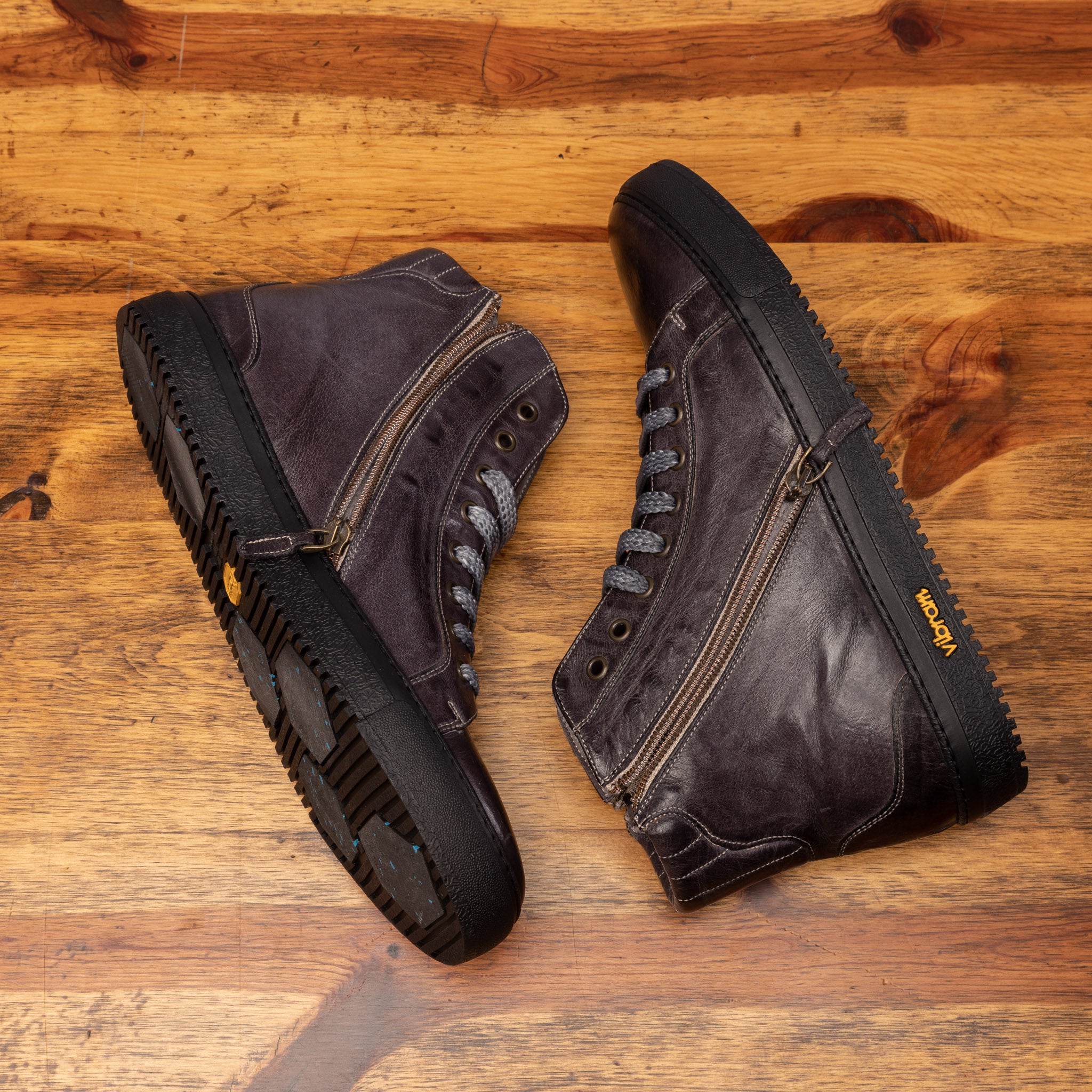 Side profile of Q555 Calzoleria Toscana Stone Dip-Dyed Buff Calf High Top showing the functional inside zipper on top of a wooden table