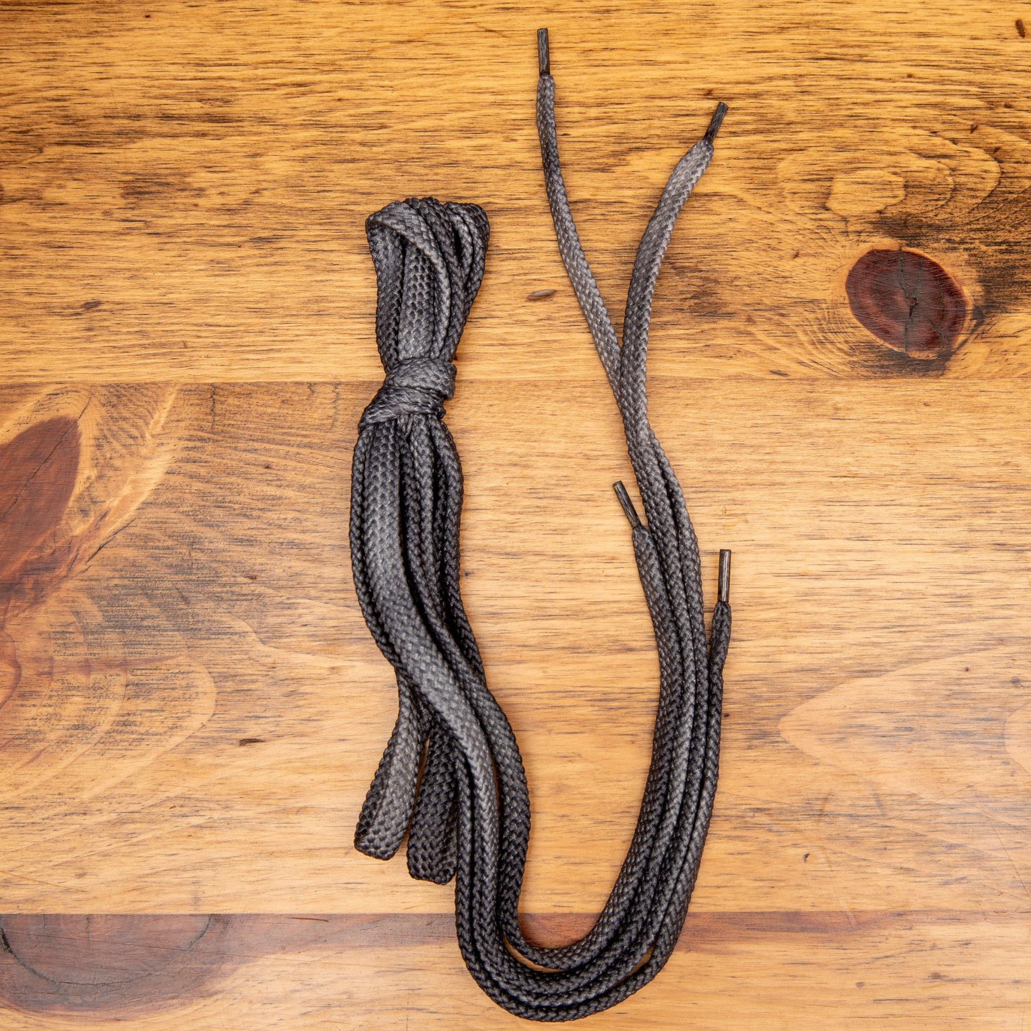 Gray Pair of  Dip-Dyed Cotton Calzoleria Toscana Laces on top of a wooden table