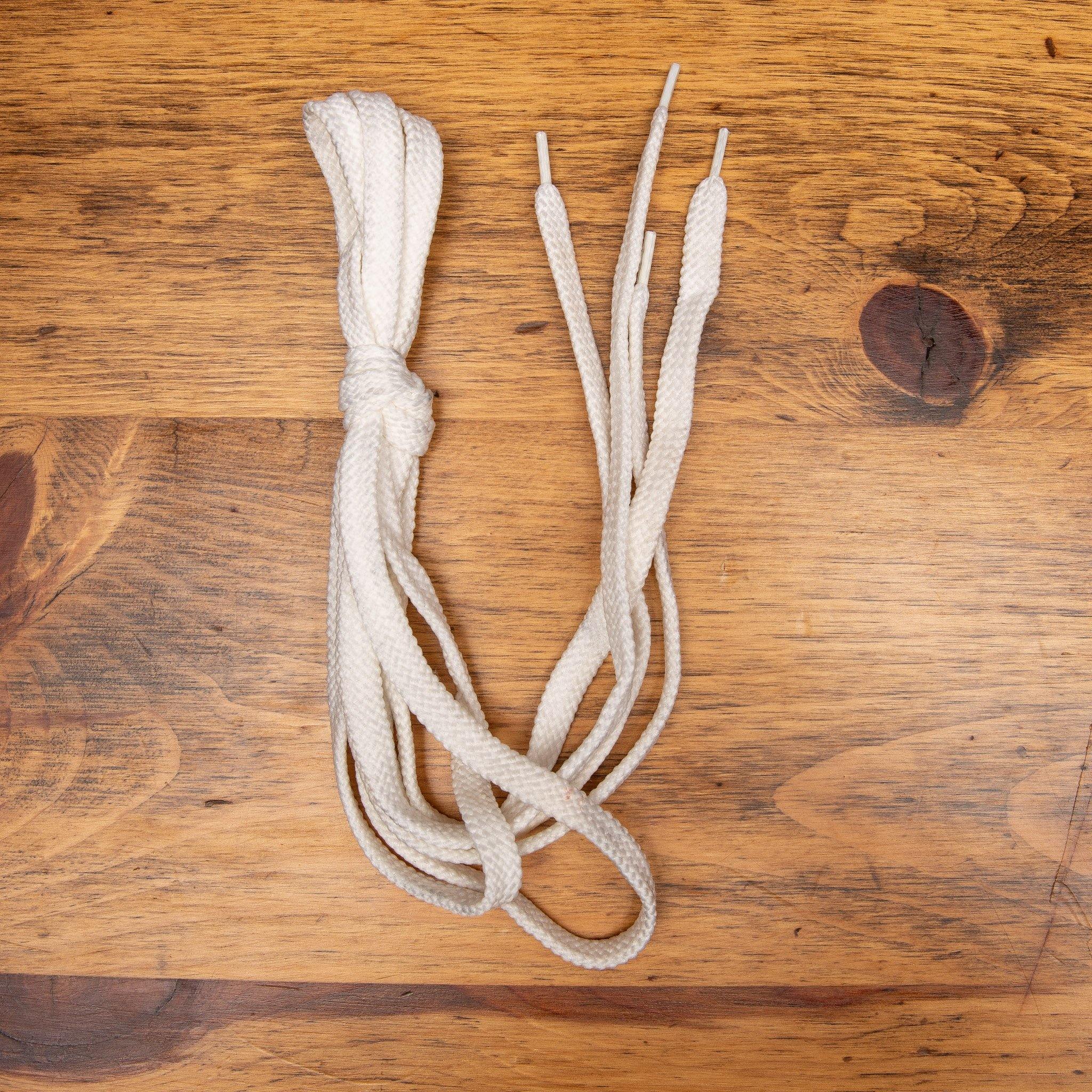 White Pair of  Dip-Dyed Cotton Calzoleria Toscana Laces on top of a wooden table