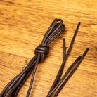 Up close picture of Brown Calzoleria Toscana Waxed Cotton Lace on top of a wooden table
