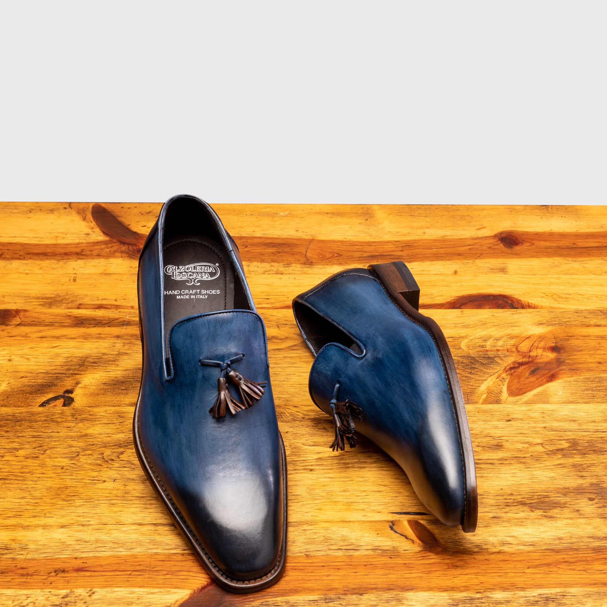 Pair of Z993 Calzoleria Toscana Ocean Blue David Tassel Slip-On showing the brand name label on top of a wooden table