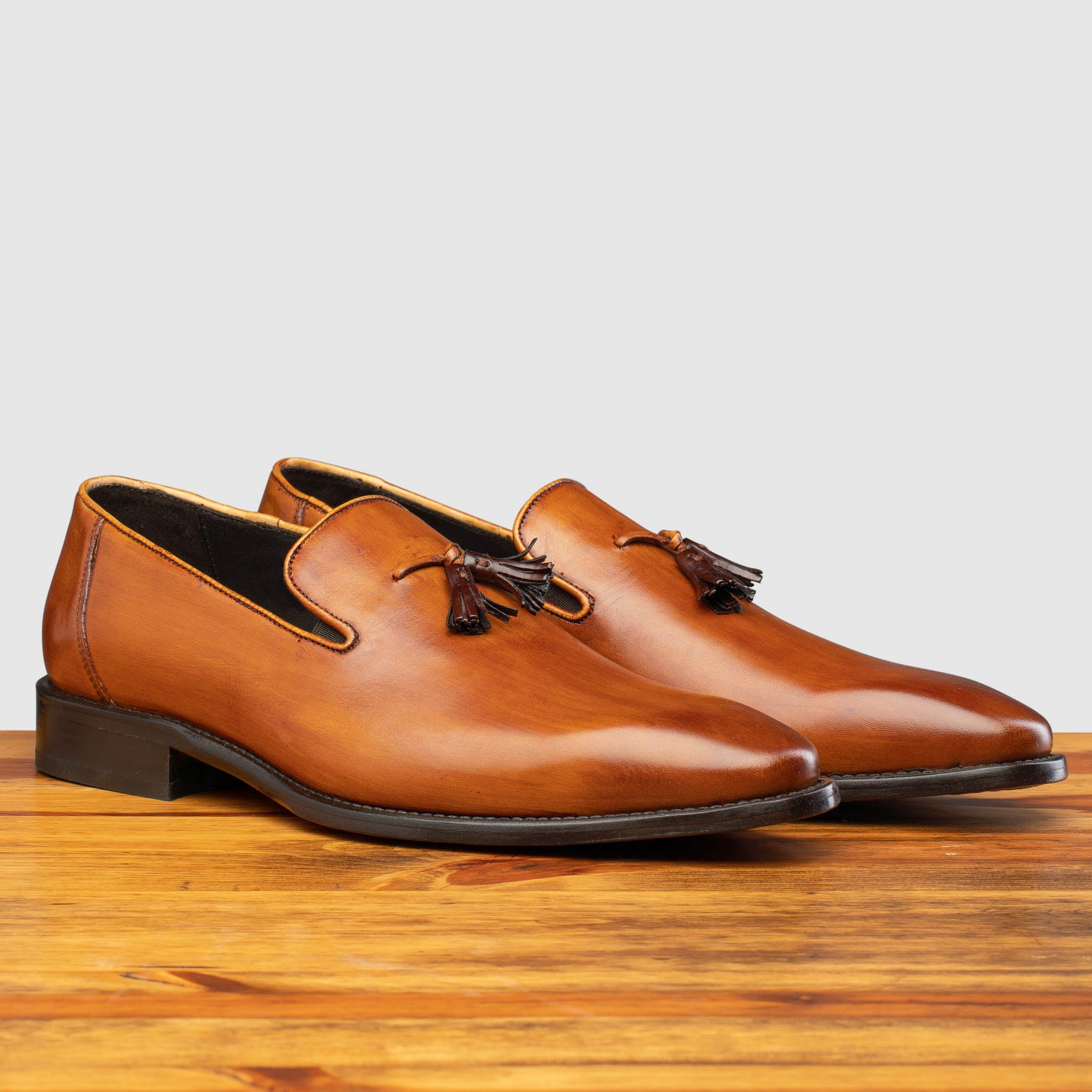 Pair of Caramel leather loafer with a tassel on a wooden surface