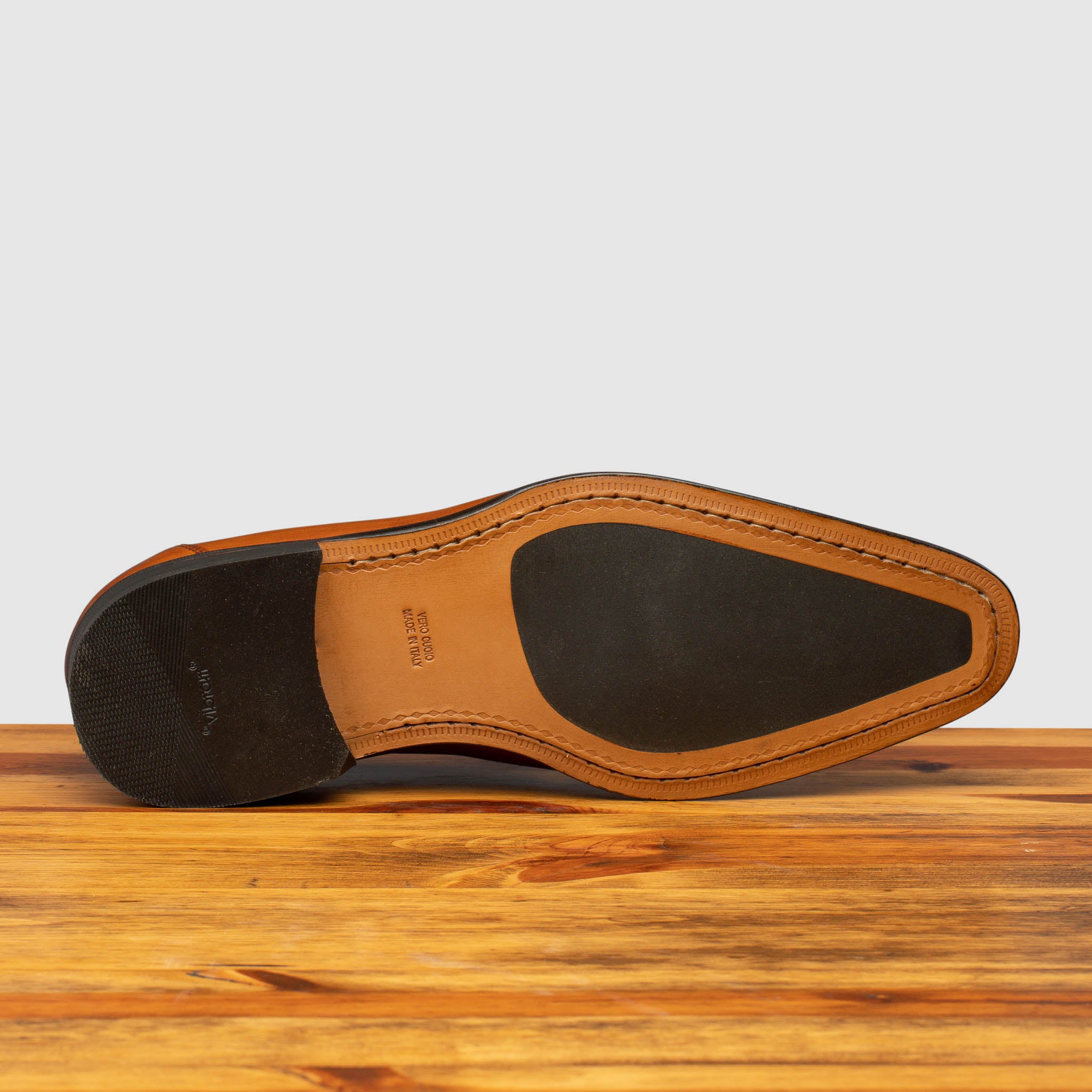 Outsole of Caramel leather loafer with a tassel on a wooden surface