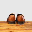 Back profile of Z993 Calzoleria Toscana Dark Caramel David Tassel Slip-On on top of a wooden table