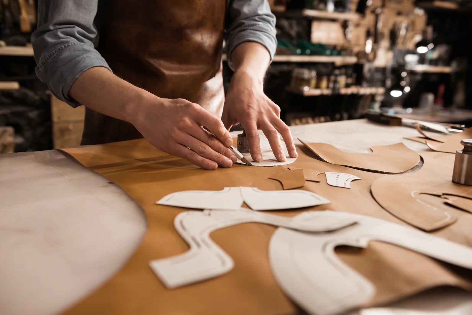 A Calzoleria Toscana artisan hand-cutting leather pattern pieces for shoes in the Italian workshop.